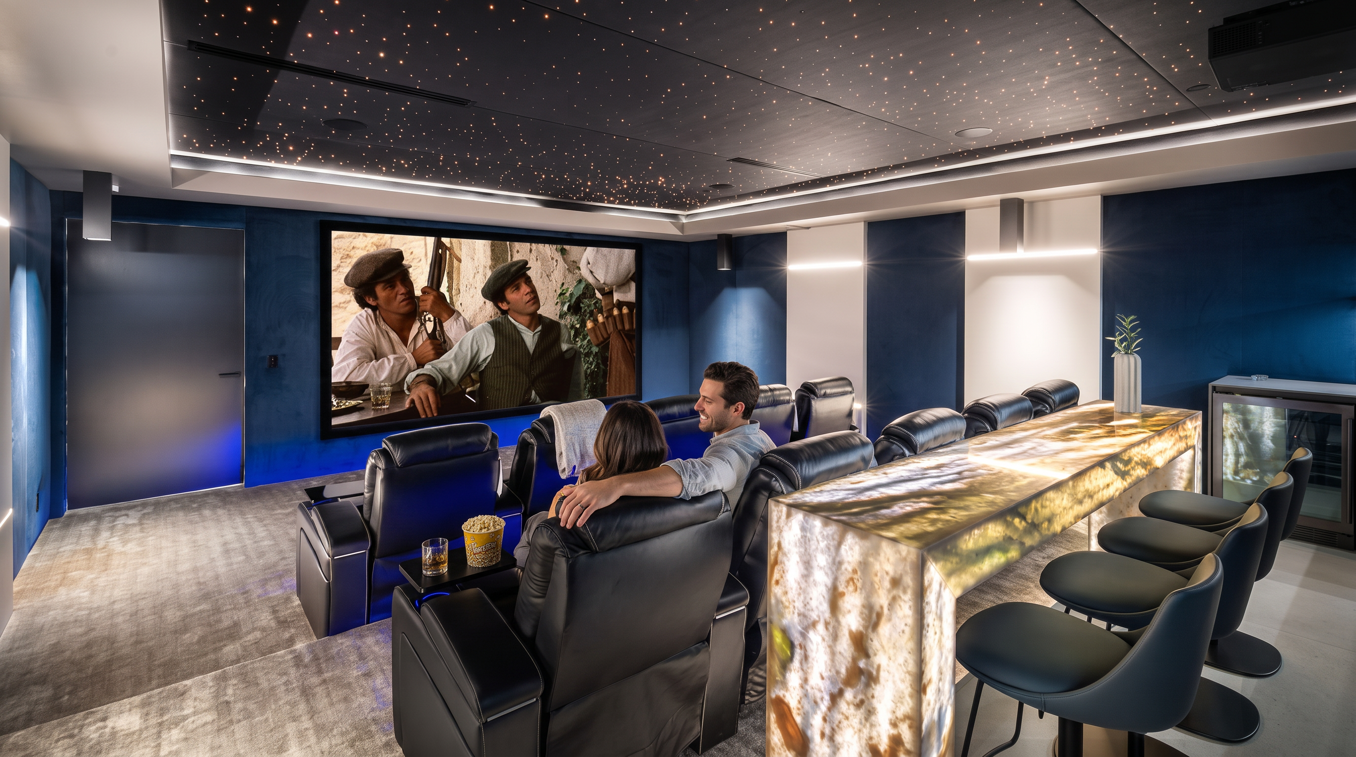This luxurious home theater is designed for an optimal cinematic experience, featuring tiered rows of comfortable leather seating, a large projection screen, and a starry-night ceiling treatment. Behind the primary seating area is an illuminated marble bar with high-end stools, perfect for hosting or refreshments. The space is finished with deep blue velvet wall panels, plush carpeting, and sophisticated lighting, creating an elegant and immersive entertainment environment.