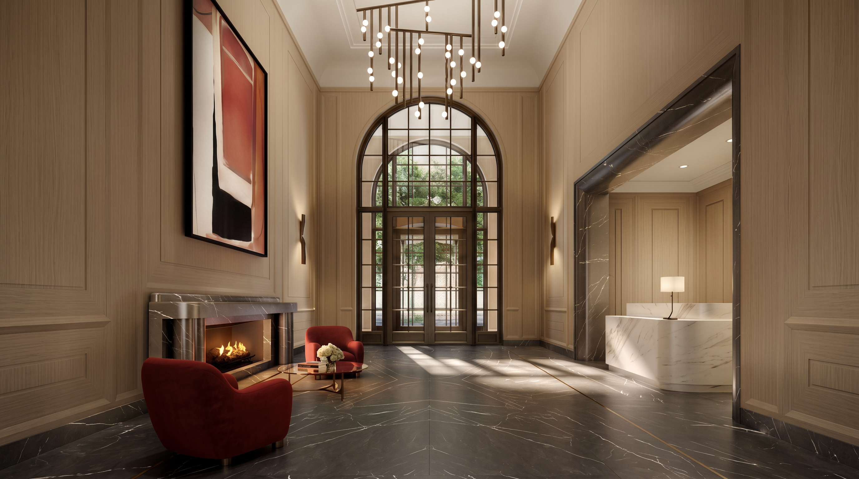 This sophisticated lobby or entryway features a grand, symmetrical design with dark stone flooring accented by a gold inlay border. A striking, multi-tiered modern chandelier hangs from the high ceiling, drawing the eye toward the arched glass entry doors at the rear. To the left, a cozy seating area with red armchairs is arranged around a fireplace, while a sleek reception desk with a lamp sits to the right, creating an inviting and luxurious atmosphere.