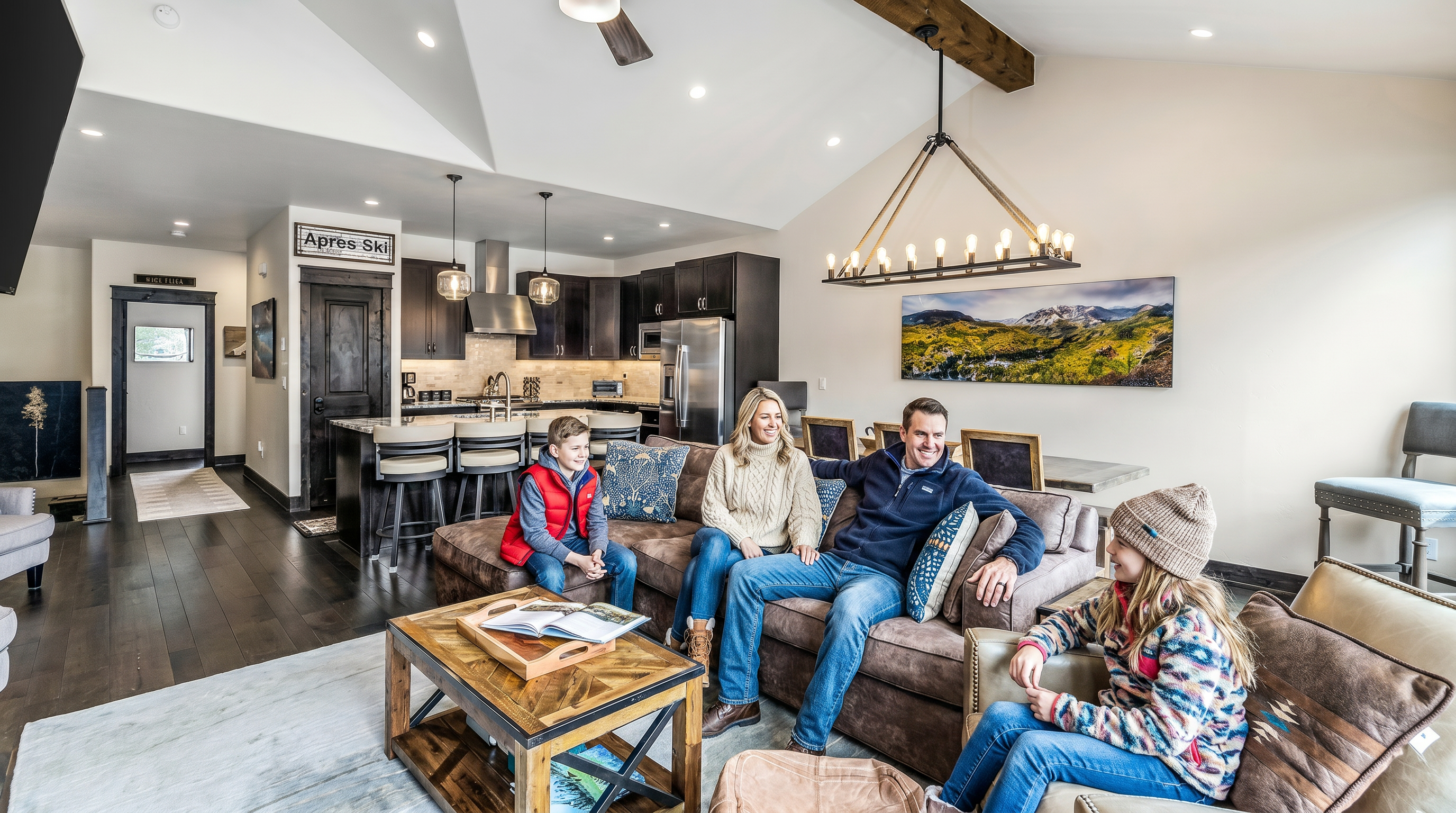 This spacious, open-concept living area features a vaulted ceiling with exposed wooden beams and a large, comfortable brown sectional sofa as its centerpiece. The room seamlessly integrates a modern kitchen with a breakfast bar and a dining area, all accented by rustic, mountain-inspired decor and warm lighting. The perspective captures the inviting, cohesive flow of the home, highlighting the blend of luxury and cozy, lodge-style aesthetics.