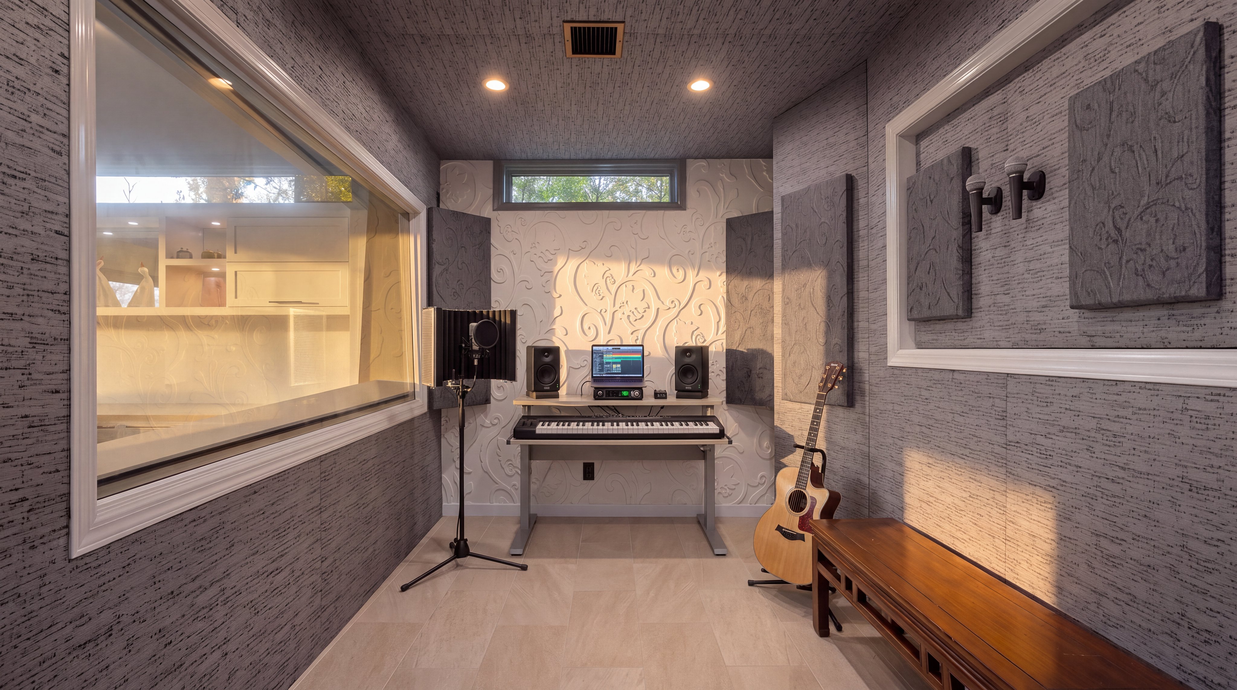 This professional-grade sound recording studio is equipped with acoustic panels, a keyboard workstation, and high-quality speakers, making it an ideal space for music production. The room features elegant decorative wall textures, integrated lighting, and a viewing window that looks into an adjacent kitchen space. This dedicated media or music studio adds significant value and appeal to a home listing for creative professionals or hobbyists.