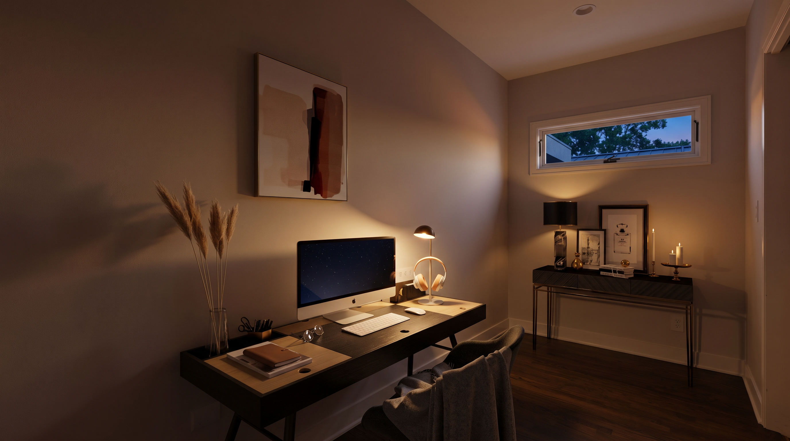 This modern home office features a sleek, dark-toned desk positioned against a crisp white wall, accented by a contemporary abstract art piece. A gray upholstered chair with a draped throw blanket provides a comfortable workspace, while a separate console table with decorative items adds a touch of sophistication. The room is illuminated by natural light from a horizontal window, creating a bright and professional atmosphere.