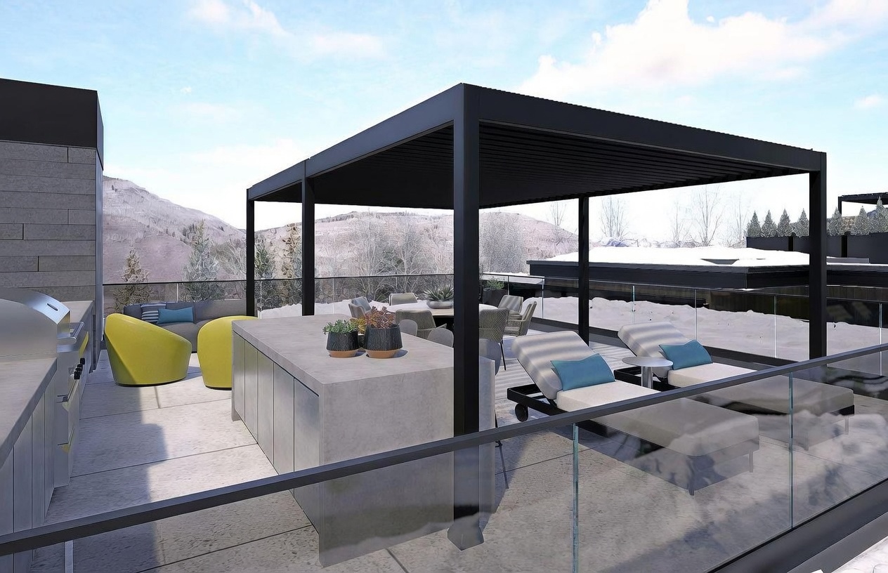 This expansive rooftop terrace offers a sophisticated outdoor living space with a modern black pergola providing shade over a dining area and lounge seating. The deck features a sleek concrete outdoor kitchen island, contemporary yellow chairs, and two chaise lounges, all set against a backdrop of snowy mountain peaks. The perspective is elevated, showcasing the seamless integration of luxury outdoor amenities with a panoramic alpine view.