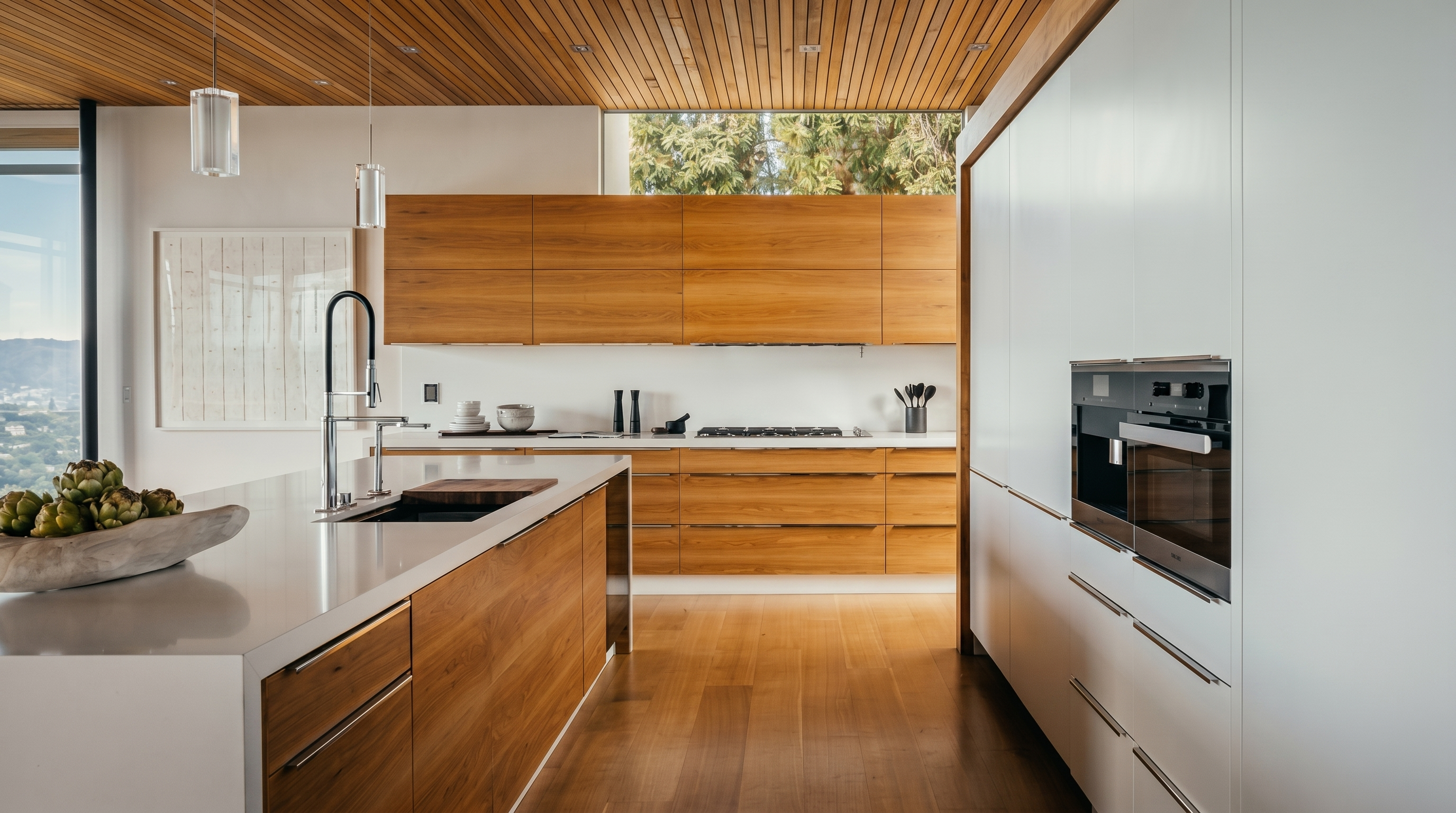 This modern kitchen features a sleek, minimalist design with warm wood cabinetry and a large central island topped with a white surface. The space is defined by a slatted wood ceiling and a wall of white cabinetry that integrates built-in appliances, creating a clean and cohesive aesthetic. A horizontal window above the backsplash provides natural light and a view of the outdoors, while pendant lights hang over the island to complete the sophisticated look.