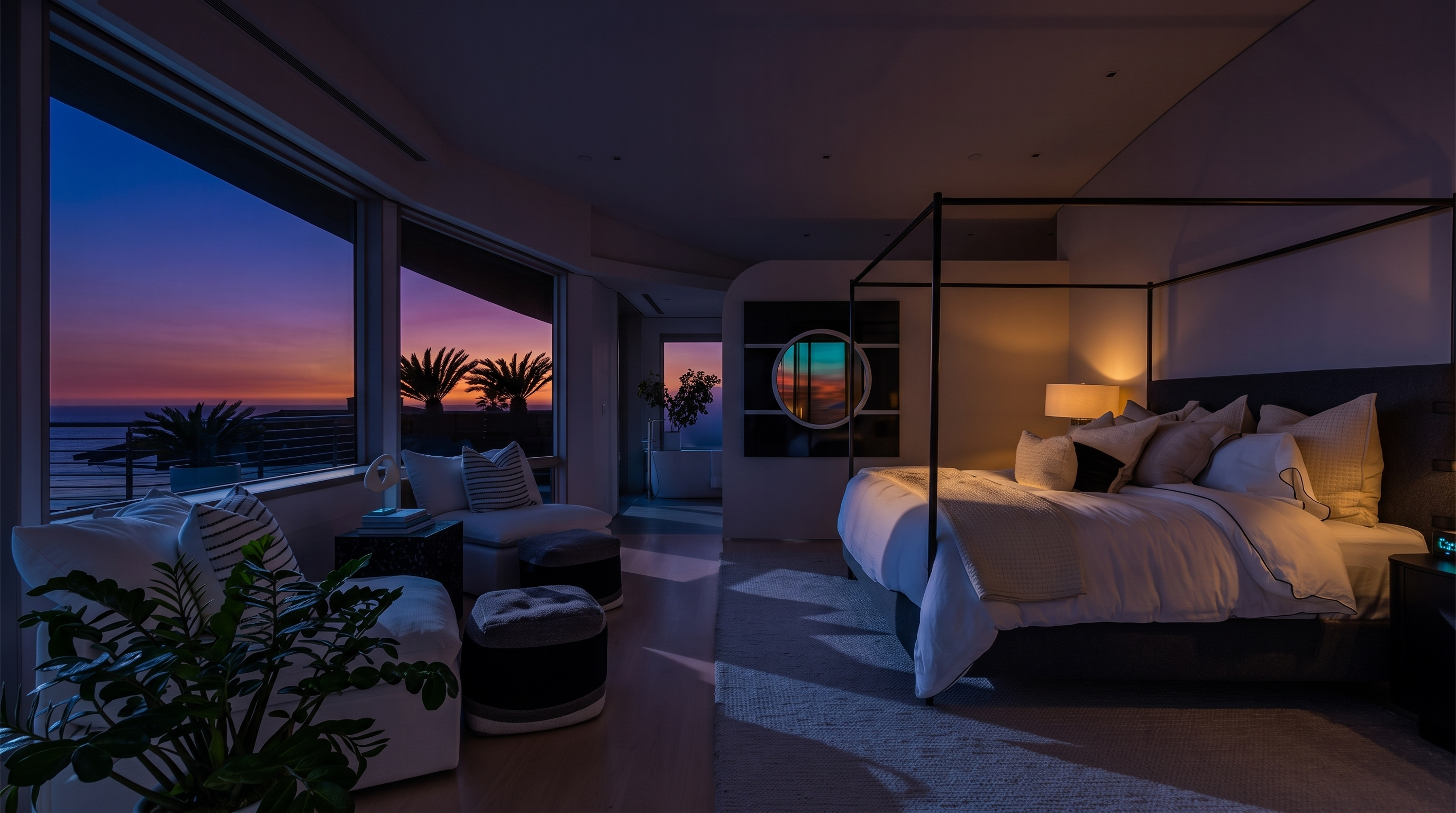 This expansive primary bedroom features a modern four-poster bed as the centerpiece, set against a neutral color palette with soft textures. Large windows provide an unobstructed view of the ocean, bathing the room in natural light and creating a serene, airy atmosphere. The space includes a cozy seating area with plush chairs and ottomans, leading toward an open-concept bathroom area in the background.