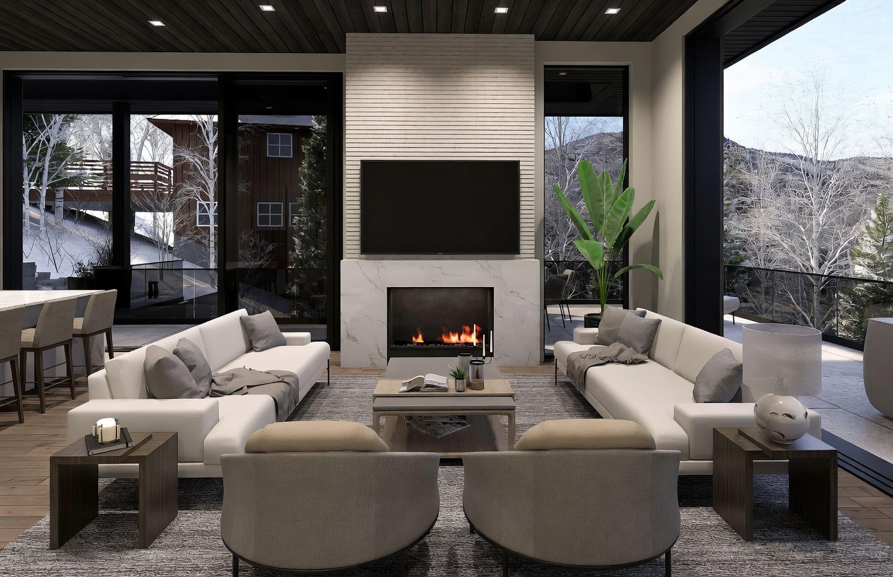 This sophisticated living room features a symmetrical layout with two white sofas facing each other across a central coffee table, anchored by two plush armchairs in the foreground. A central fireplace with a tall stone surround serves as the focal point, topped by a large television. The space is framed by expansive glass walls that offer panoramic views of a snowy, wooded landscape, creating a seamless connection between the modern interior and the natural environment.