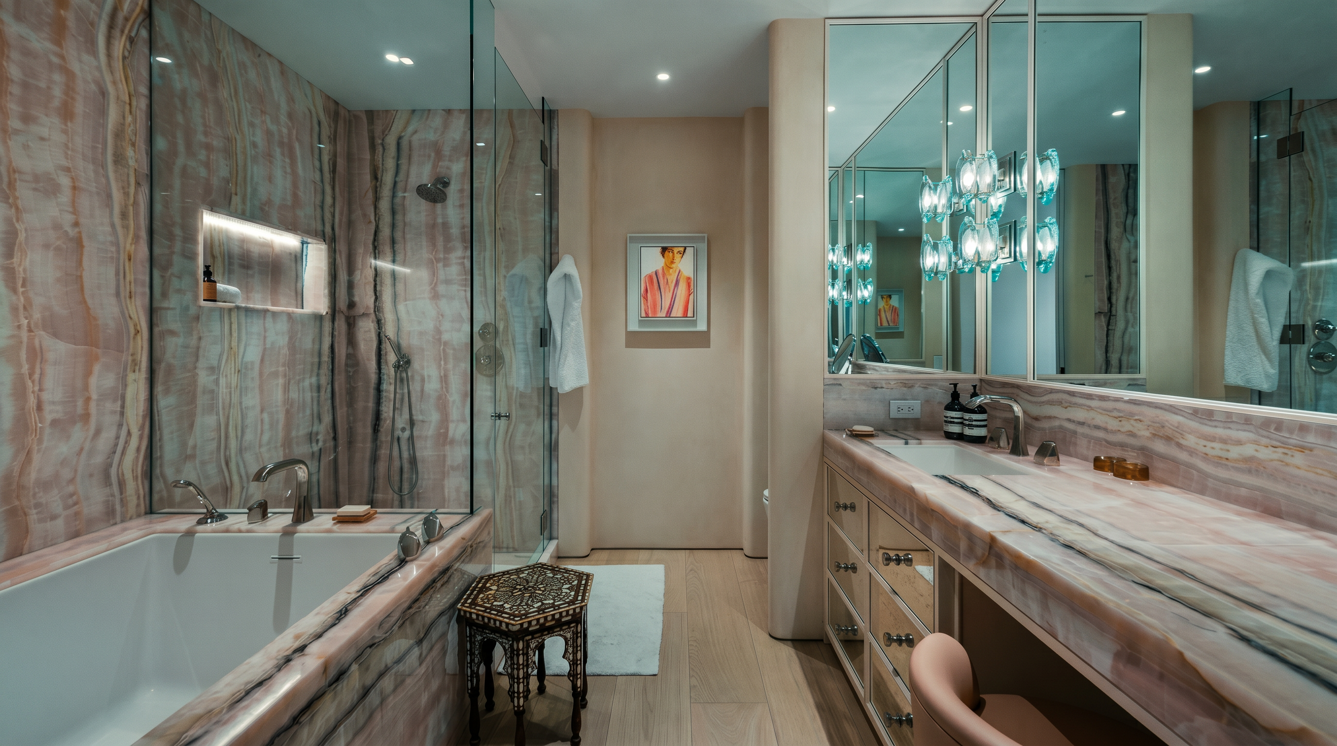 This luxurious primary bathroom features extensive use of pink-toned, veined stone on the walls, vanity, and bathtub surround. The space includes a glass-enclosed shower, a built-in vanity with a stool, and a large mirror reflecting a decorative chandelier. The light wood flooring and soft, neutral wall tones create a sophisticated and serene atmosphere.