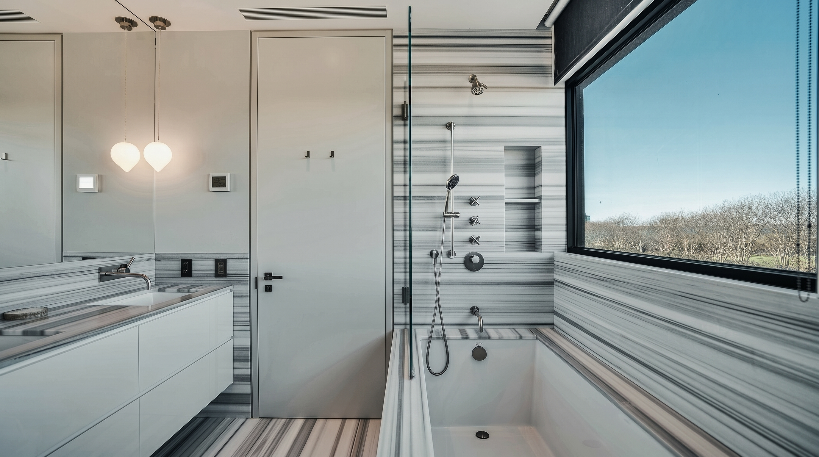 This modern primary bathroom features striking horizontal-striped stone wall cladding that extends from the vanity area into the shower and tub surround. A sleek white floating vanity with a minimalist faucet sits beneath a large mirror, while a glass-enclosed shower and soaking tub combination offers a clean, spa-like aesthetic. A large window provides natural light and an expansive view of the outdoors, enhancing the bright and airy atmosphere of the space.