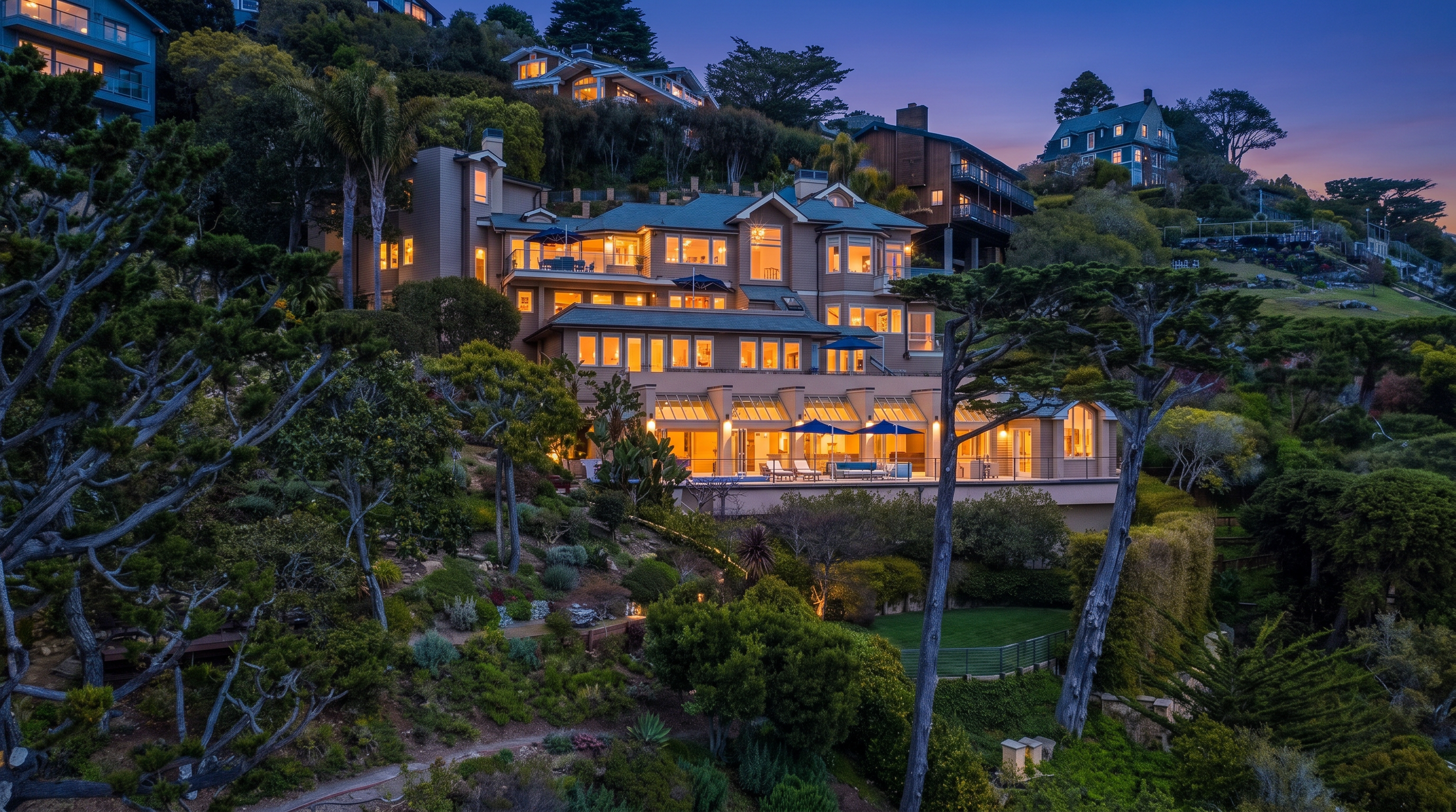 This expansive multi-level residence is nestled into a lush, terraced hillside, showcasing a sophisticated architectural design with multiple balconies and large windows that capture the surrounding landscape. The rear of the home features a tiered layout with a swimming pool area on the lower level, surrounded by mature trees and manicured greenery. The perspective is captured from an elevated, slightly angled vantage point, emphasizing the home's integration into the steep, scenic terrain.
