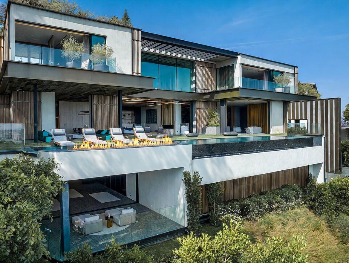 This stunning contemporary luxury residence features a multi-level architectural design with expansive glass walls, wood-slatted accents, and a seamless indoor-outdoor flow. The rear exterior showcases a sleek infinity-edge pool with an integrated fire feature, overlooking a lower-level covered patio lounge area. The property exudes a sophisticated, resort-like atmosphere, perfectly blending modern structural elements with lush, manicured landscaping.