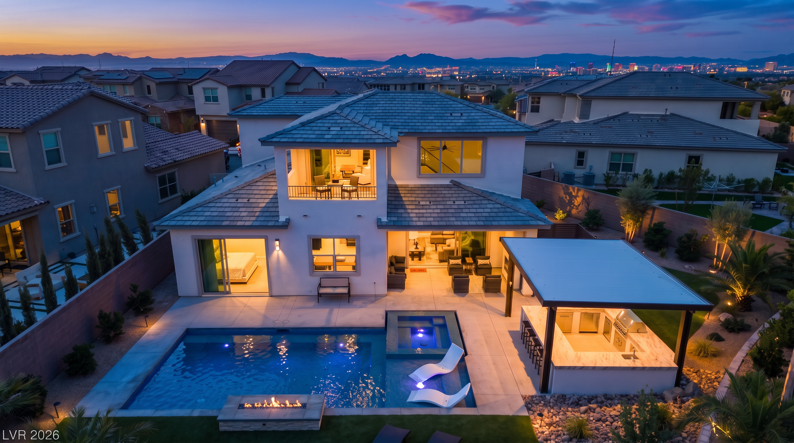 This stunning aerial view captures a contemporary two-story residential home during a picturesque dusk. The backyard features a sparkling pool and spa, a cozy built-in fire feature, and a modern outdoor kitchen covered by a sleek patio structure. With warm interior lighting radiating through large windows and a balcony, the property offers a luxurious and inviting atmosphere perfect for outdoor entertaining.