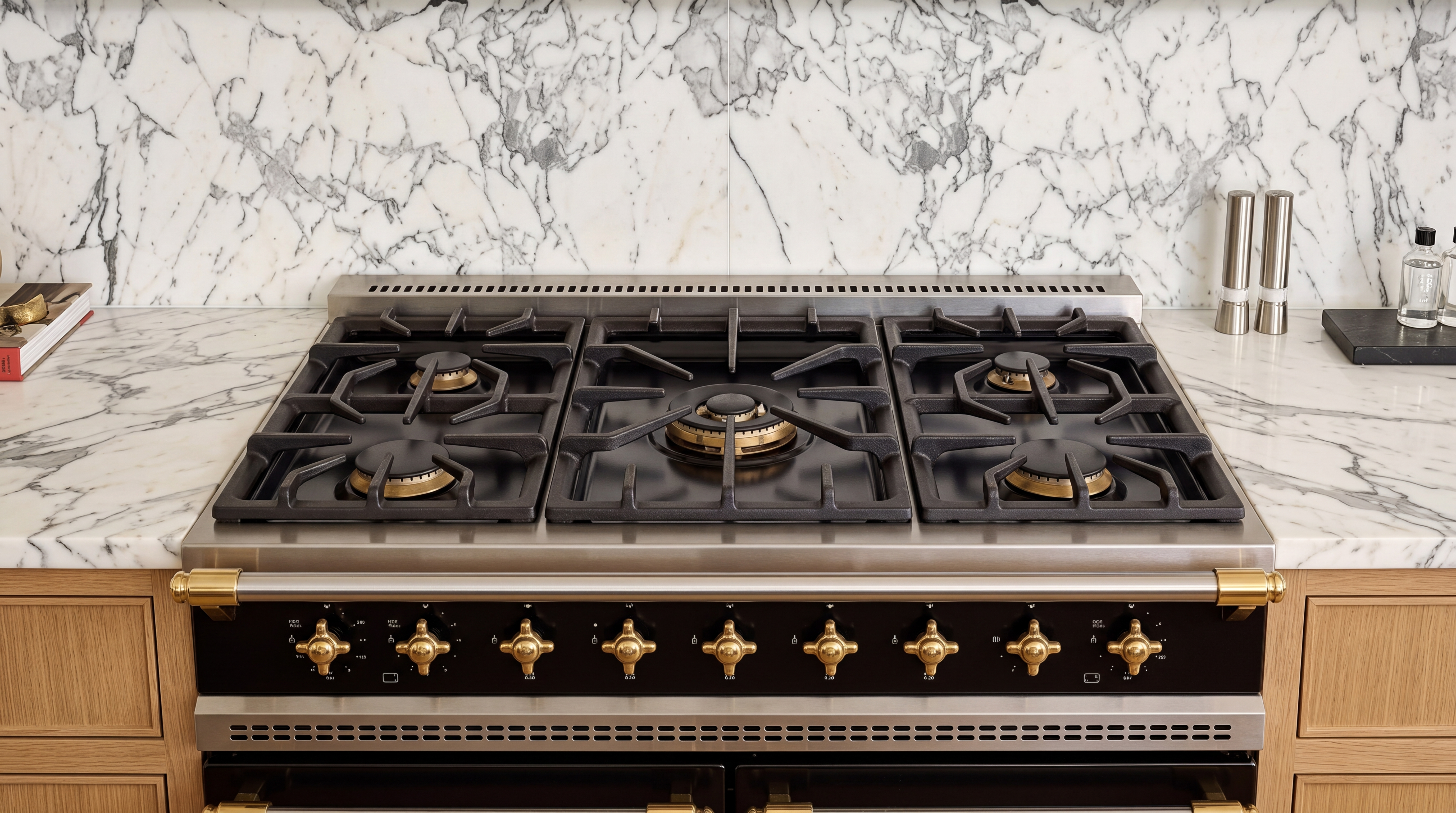 This image showcases a high-end, professional-style gas range with a sleek black and brass aesthetic integrated into a marble countertop and backsplash. The clean lines and premium materials convey a luxurious, sophisticated culinary space perfect for home chefs. The addition of wood-toned cabinetry and matching salt and pepper grinders adds a touch of organic warmth to the refined design.