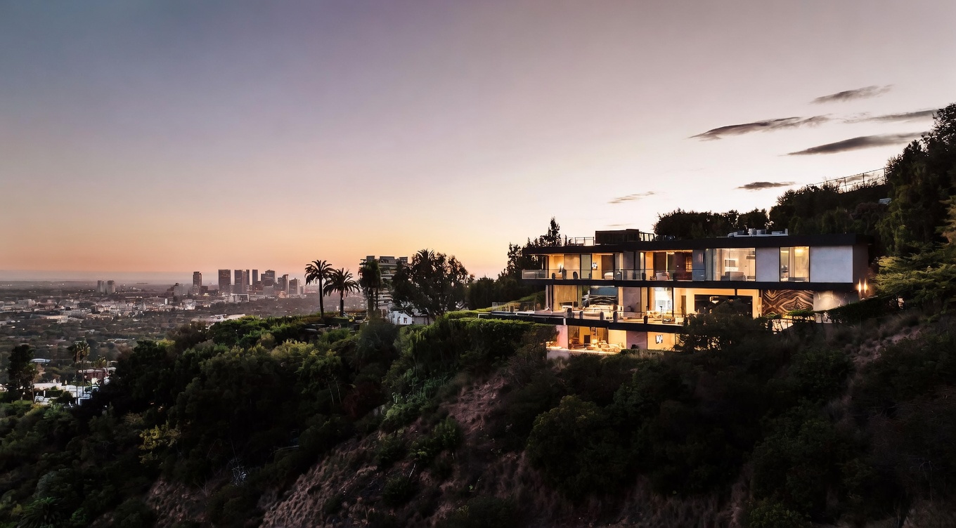 This stunning aerial shot captures a luxurious, multi-level modern residence perched dramatically on a hillside overlooking a sprawling city skyline at dusk. The home features expansive glass walls, sleek architectural lines, and integrated outdoor living spaces that blend seamlessly with the natural landscape. The warm glow from the interior lighting contrasts beautifully against the soft, twilight-hued sky, creating an atmosphere of sophisticated elegance and exclusivity.