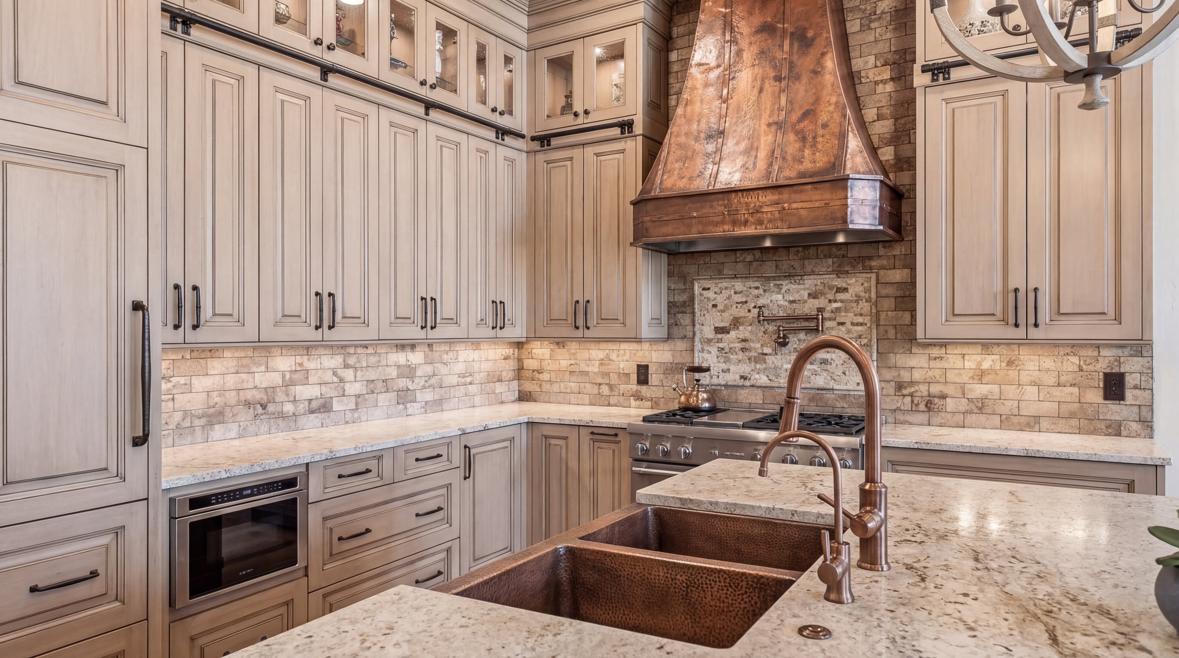This elegant and warm kitchen features custom light-toned wood cabinetry, stone countertops, and a striking hammered copper dual-basin sink and vent hood. The space is accented by a textured brick backsplash, high-end stainless steel appliances, and a farmhouse-inspired aesthetic that exudes rustic luxury. The integrated design and coordinated metallic elements create a cohesive, high-end feel perfect for a luxury real estate listing.