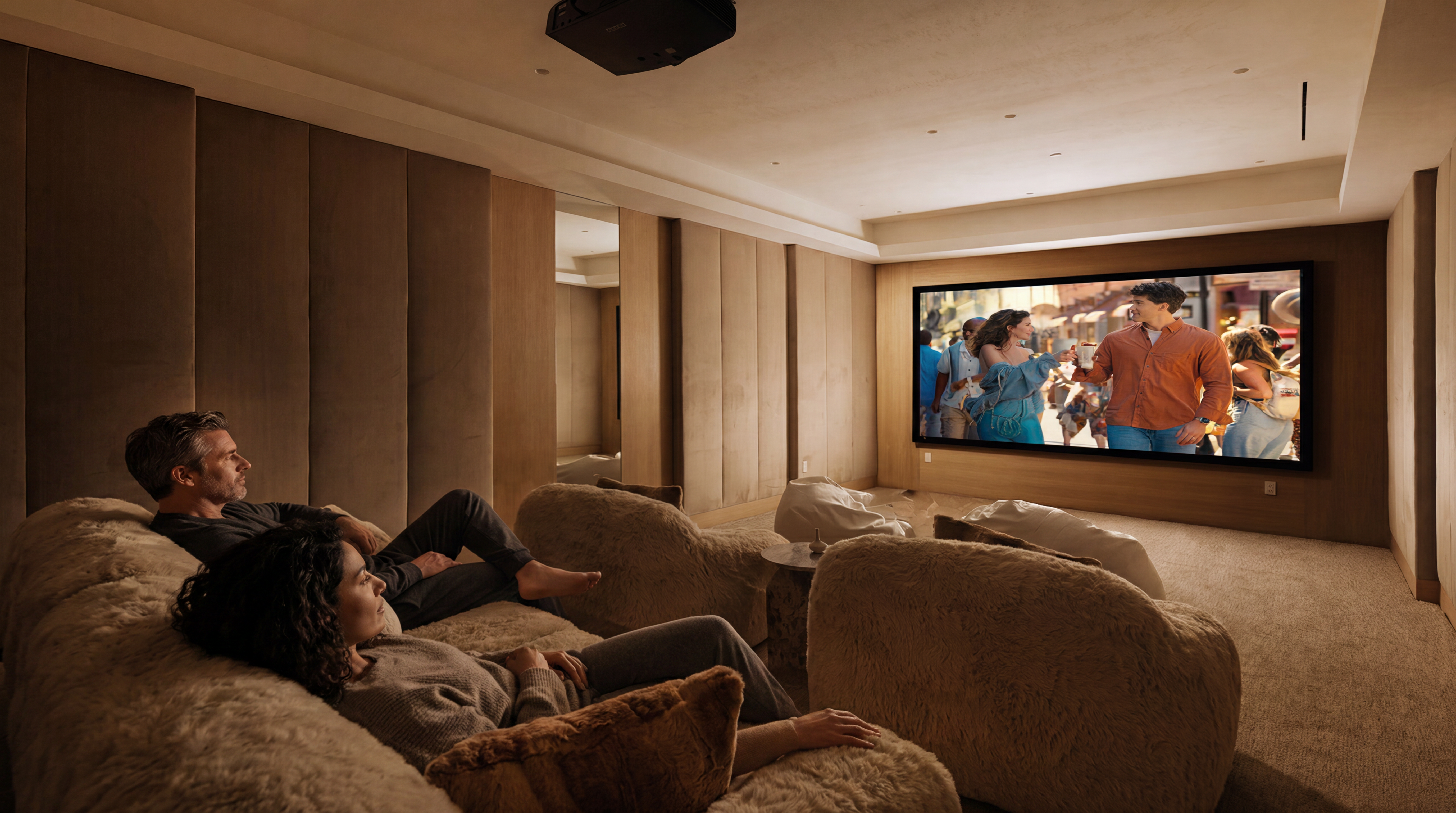This luxurious home theater room features plush, textured seating and sophisticated wall paneling for an immersive viewing experience. The room is equipped with a large projection screen and a ceiling-mounted projector, creating a private cinema environment perfect for entertaining. With its warm lighting and cozy atmosphere, this space adds significant value and appeal to a high-end residential property.