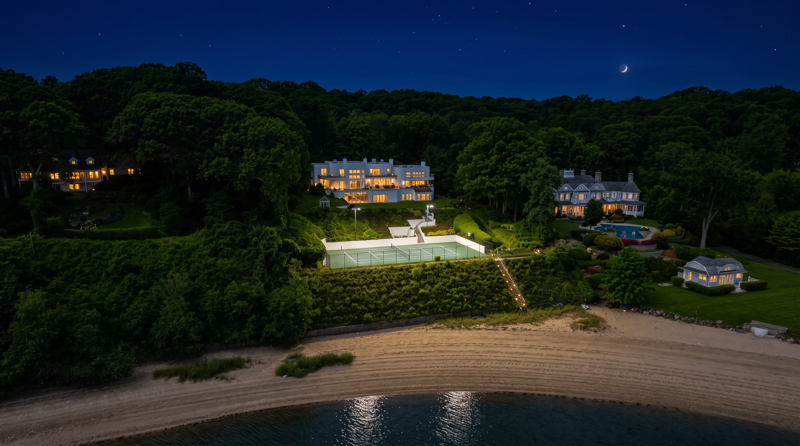 This stunning waterfront estate features multiple luxurious residences nestled within a lush, forested landscape overlooking a private sandy beach. The expansive property includes premier amenities such as a dedicated tennis court and a sparkling swimming pool, offering a perfect blend of privacy and recreation. With its elevated positioning and direct ocean access, the property exudes an air of sophisticated coastal elegance.