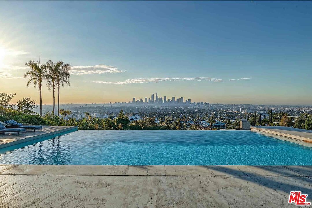 This image showcases a luxurious infinity pool with a stunning panoramic view of the city skyline. Palm trees add a touch of tropical elegance, while lounge chairs invite relaxation. The pool's design seamlessly blends with the horizon, creating a sense of serenity and sophistication.