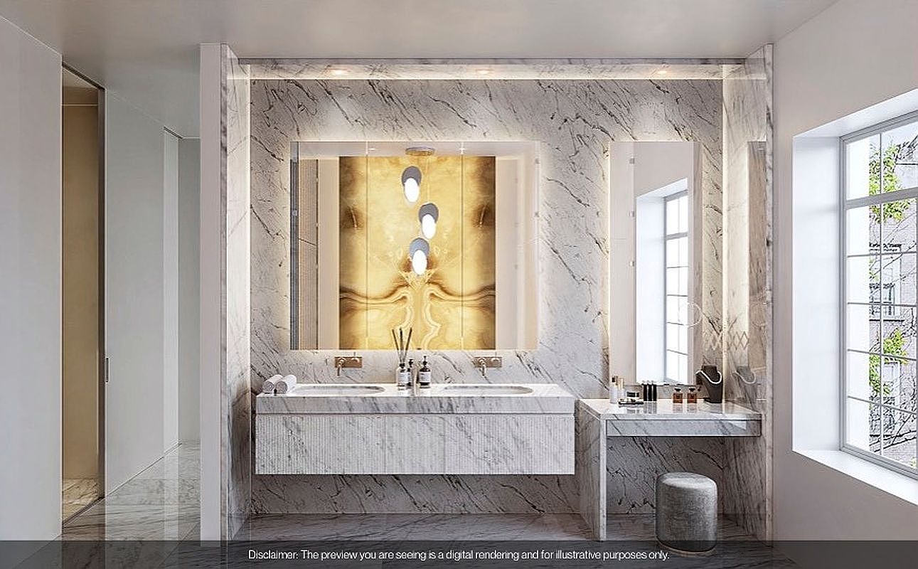 This is a luxurious primary bathroom featuring marble walls and flooring, creating a sophisticated and elegant ambiance. A double vanity with integrated sinks and a makeup area are illuminated by modern lighting fixtures. The space is designed with clean lines and high-end finishes, offering a spa-like experience.