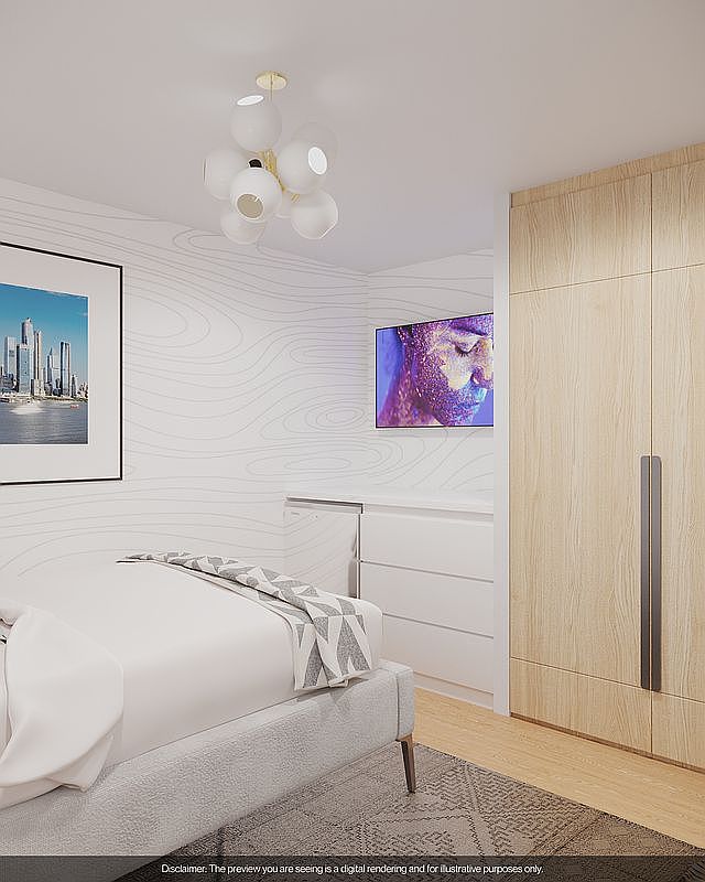 This is a bedroom interior featuring a bed with white linens and a patterned throw, a modern light fixture, and a wall-mounted television. The room has a minimalist design with a light color palette, including a light wood wardrobe and white dresser. The perspective is from the foot of the bed, showcasing the room's layout and design elements.