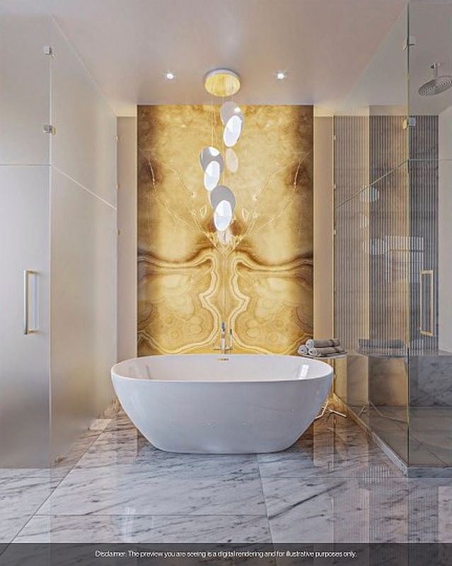This is a luxurious primary bathroom featuring a freestanding white bathtub as the focal point, set against a stunning marble-patterned wall. The room is illuminated by a modern chandelier, and the marble flooring adds to the elegant ambiance. A glass-enclosed shower is visible on the right, completing the spa-like retreat.