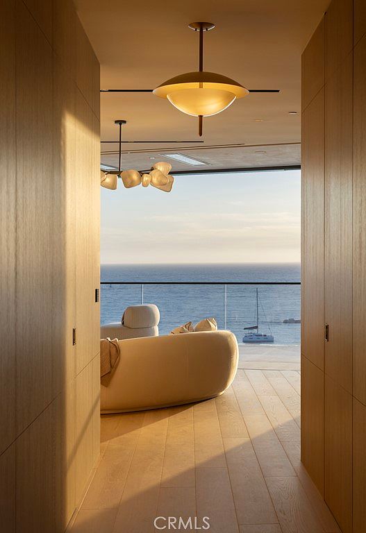 This interior shot showcases a luxurious living space with a stunning ocean view. The room features modern lighting fixtures, a comfortable-looking sofa, and hardwood flooring. The overall impression is one of elegance and tranquility, perfect for a high-end real estate listing.