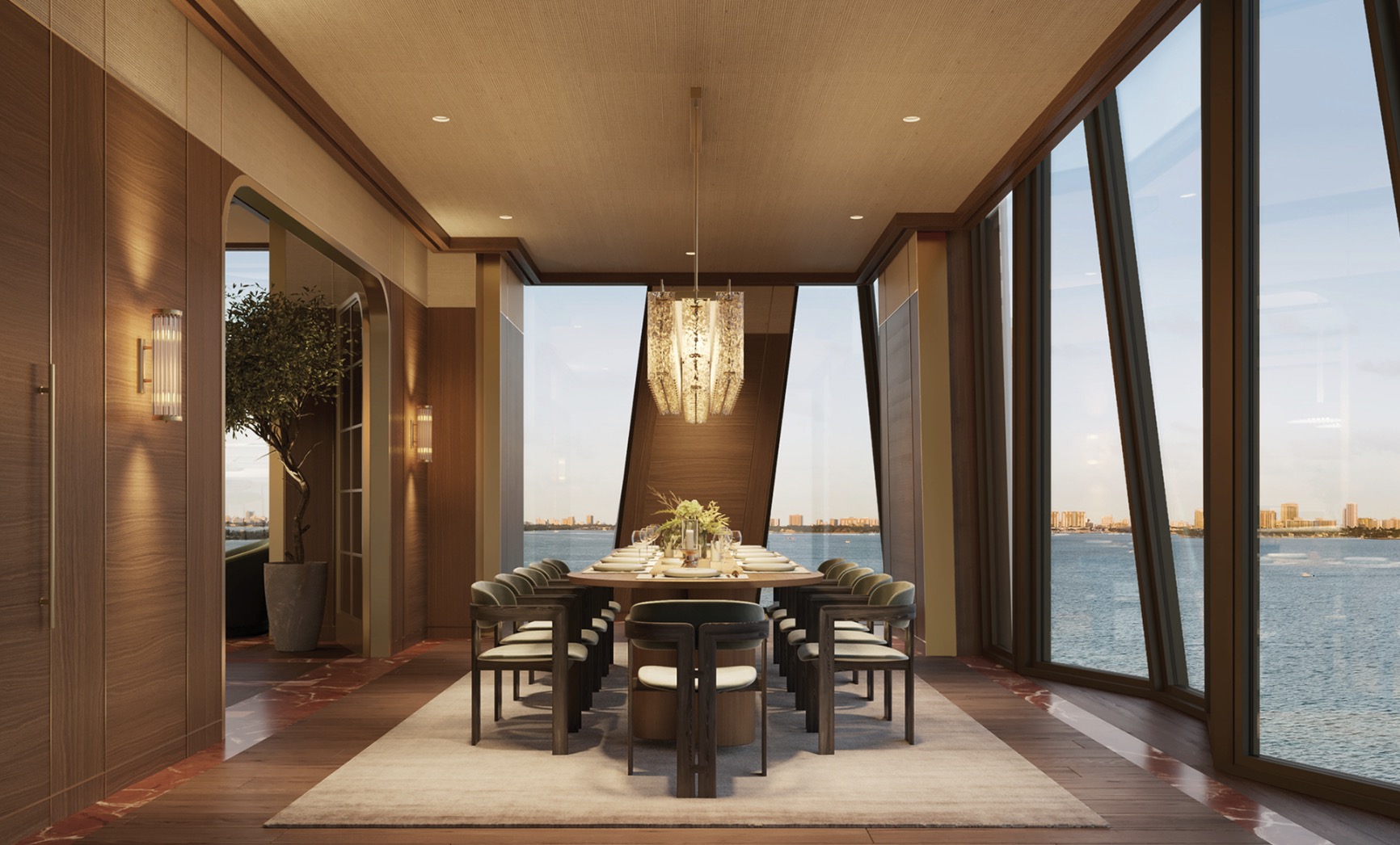 This elegant dining room features a long, oval table set for a formal meal, surrounded by modern chairs with dark wood frames and light upholstery. A unique chandelier hangs above the table, providing ambient lighting, while large windows offer stunning views of the water and cityscape. The room is decorated with wood paneling and a neutral color palette, creating a sophisticated and inviting atmosphere.