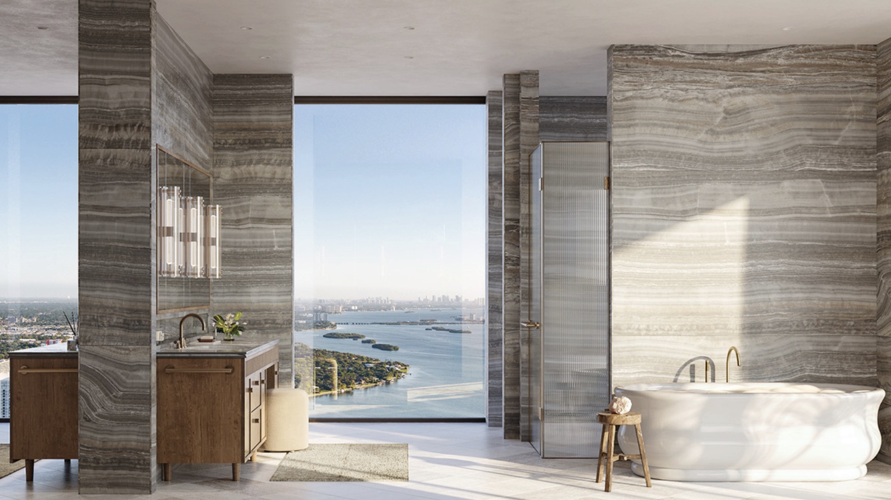 This is a luxurious primary bathroom featuring marble-like wall tiles and a stunning view of the city and ocean through a large window. The bathroom includes a freestanding bathtub, a glass-enclosed shower, and a wooden vanity with modern fixtures. The overall impression is one of elegance and tranquility, perfect for a high-end real estate listing.