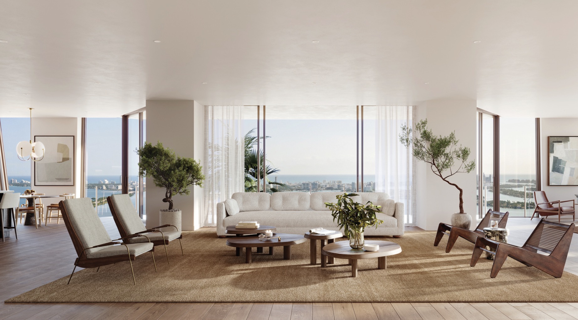This is a bright and spacious living room with floor-to-ceiling windows offering stunning ocean and city views. The room features a neutral color palette, a comfortable white sofa, and stylish modern furniture, including wooden chairs and coffee tables. The open layout and natural light create an inviting and luxurious atmosphere.