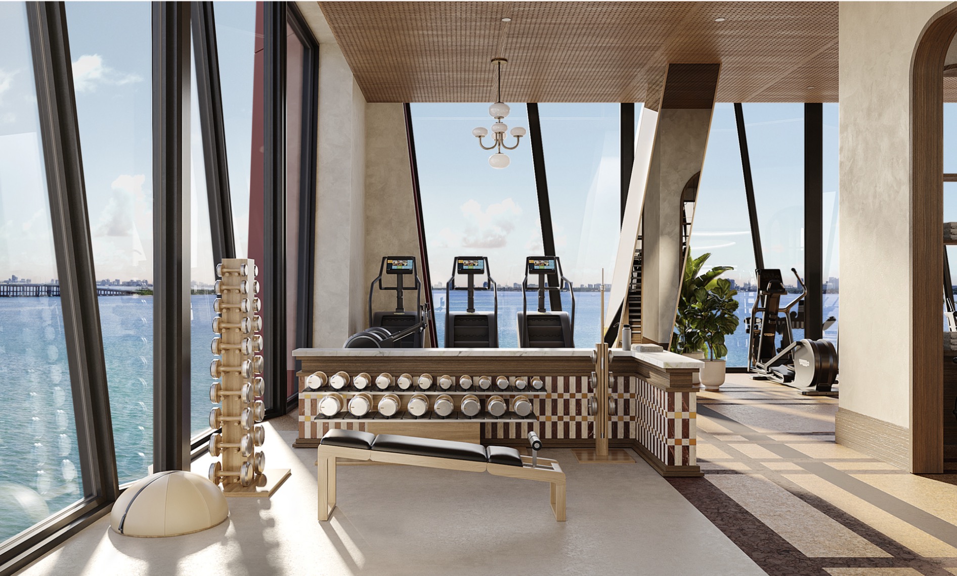 This is a modern, well-lit home gym with floor-to-ceiling windows offering stunning water views. The gym features a variety of equipment including treadmills, elliptical machines, and a dumbbell rack with a bench. The design incorporates natural wood tones and neutral colors, creating a serene and motivating workout environment.