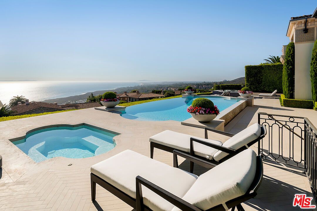 This exterior shot showcases a luxurious pool and spa area with stunning ocean views. The scene features elegant lounge chairs, manicured landscaping, and a well-maintained patio. The infinity pool blends seamlessly with the horizon, creating a serene and upscale ambiance, perfect for relaxation and entertainment.