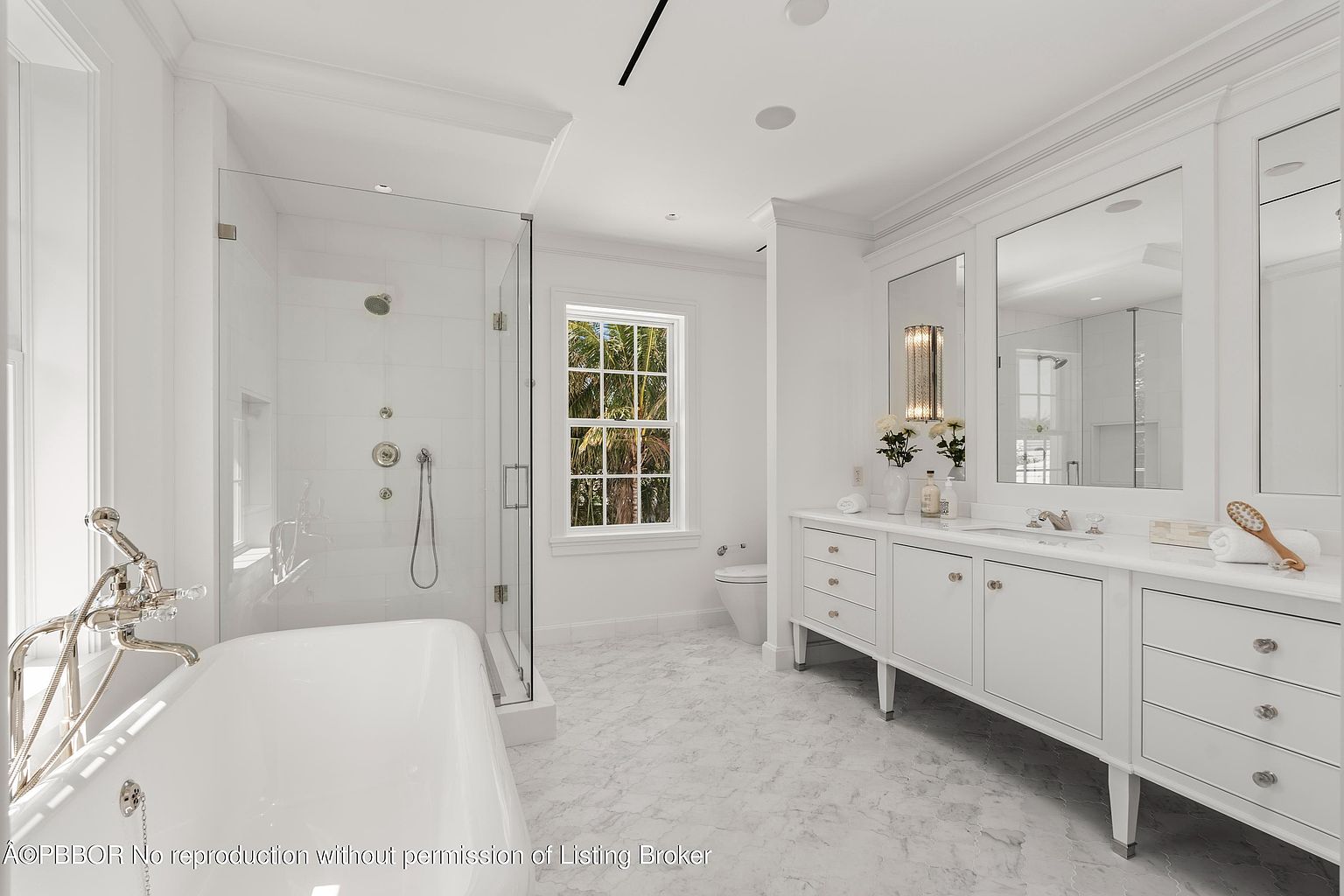 This is a luxurious primary bathroom featuring a freestanding soaking tub with chrome fixtures, a glass-enclosed shower with multiple showerheads, and a double vanity with white cabinetry and marble countertops. The room is bright and airy, with a large window providing natural light and a view of the outdoors. The flooring is marble, and the overall style is elegant and modern.