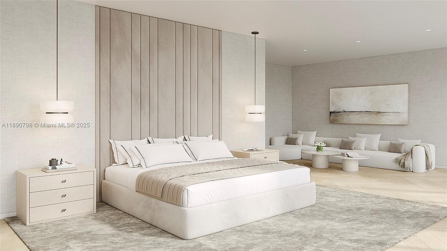 This is a serene primary bedroom featuring a large bed with white linens and a neutral-toned throw. The room is decorated in a minimalist style with a padded headboard, matching nightstands, and pendant lighting. A seating area with a sofa and artwork is visible in the background, creating a luxurious and inviting space.