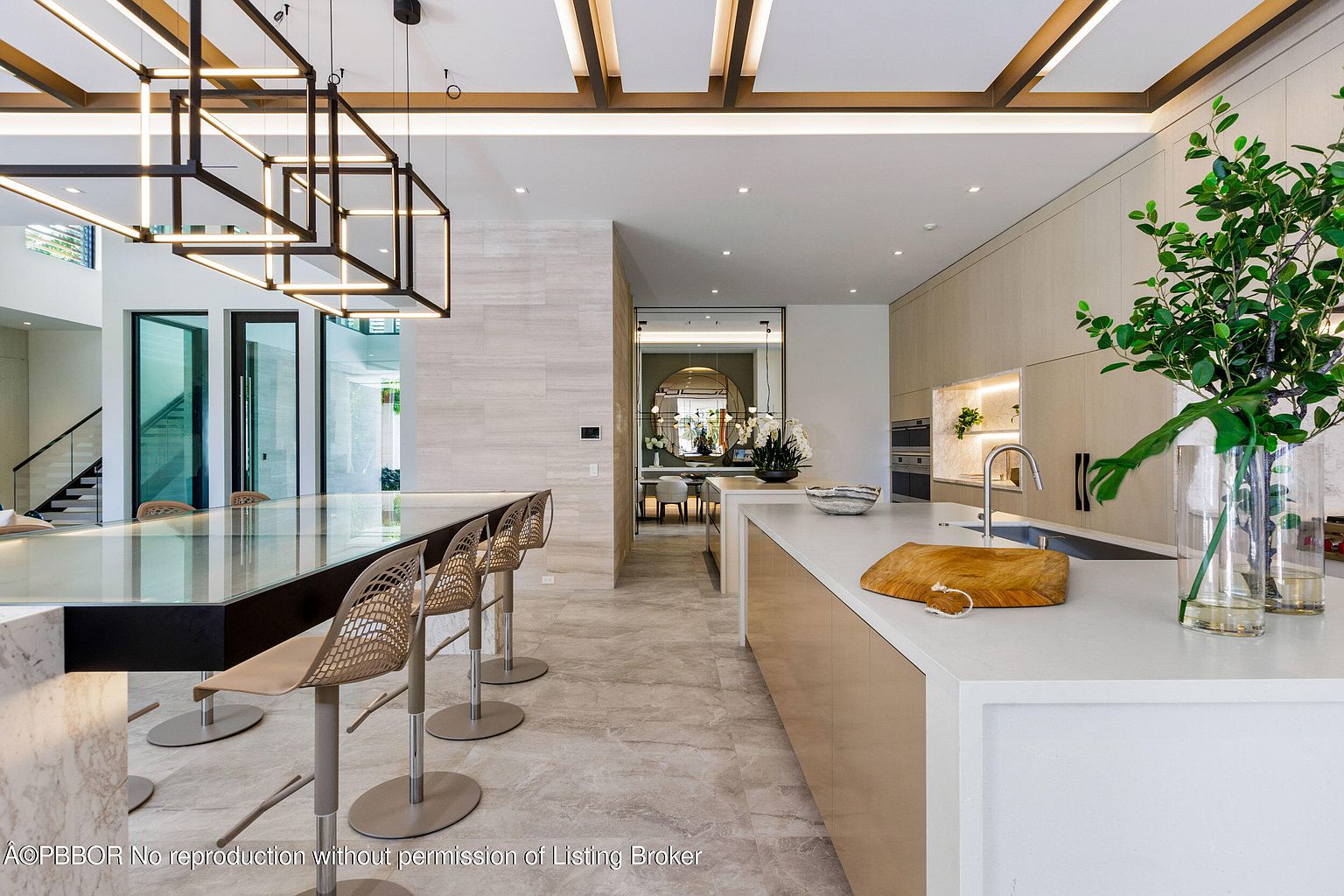 This is a bright and modern kitchen featuring a large island with seating, sleek cabinetry, and high-end appliances. The open floor plan connects to a dining area, creating a spacious and inviting atmosphere. The lighting fixtures and clean lines contribute to a contemporary aesthetic, perfect for entertaining and everyday living.