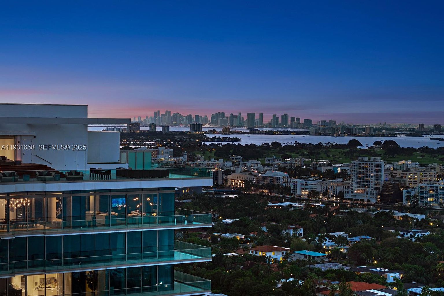 This aerial view showcases a luxury high-rise building with expansive glass balconies overlooking a vibrant cityscape at dusk. The building's modern architecture is complemented by the surrounding urban landscape, featuring lush greenery and distant city lights. The overall impression is one of sophisticated urban living with stunning panoramic views.