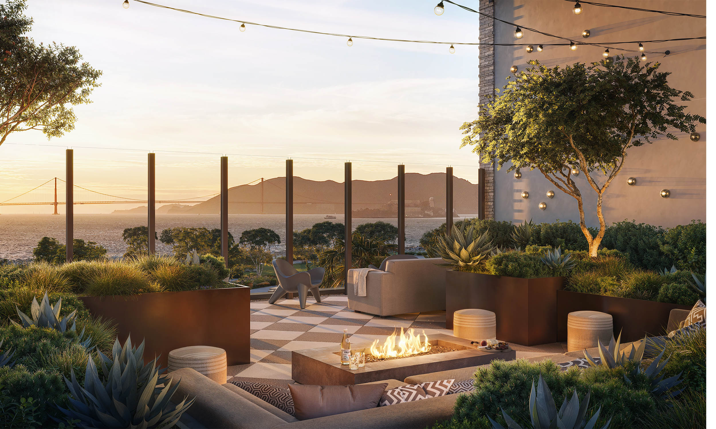 This image showcases a luxurious outdoor patio or balcony with stunning views of the Golden Gate Bridge and the bay. The space is elegantly furnished with modern seating, a fire pit, and lush greenery in planters, creating a serene and inviting atmosphere. String lights overhead add a touch of warmth and ambiance, perfect for evening relaxation or entertaining.