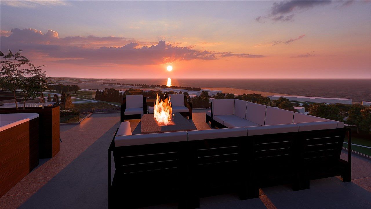 This image showcases a luxurious patio or balcony area, featuring comfortable outdoor seating arranged around a modern fire pit. The setting offers a stunning sunset view over the ocean, creating a serene and upscale ambiance. The space is designed for relaxation and entertainment, making it an attractive feature for potential buyers.