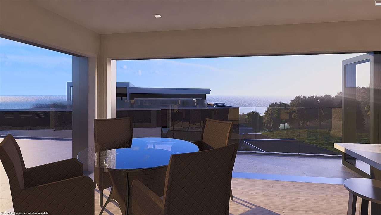 This image showcases a stylish outdoor patio or balcony area, furnished with a round glass-top table and wicker chairs. The space offers an expansive view of the ocean and surrounding landscape, suggesting a luxurious and relaxing atmosphere. The design emphasizes indoor-outdoor living, perfect for entertaining or enjoying the scenery.