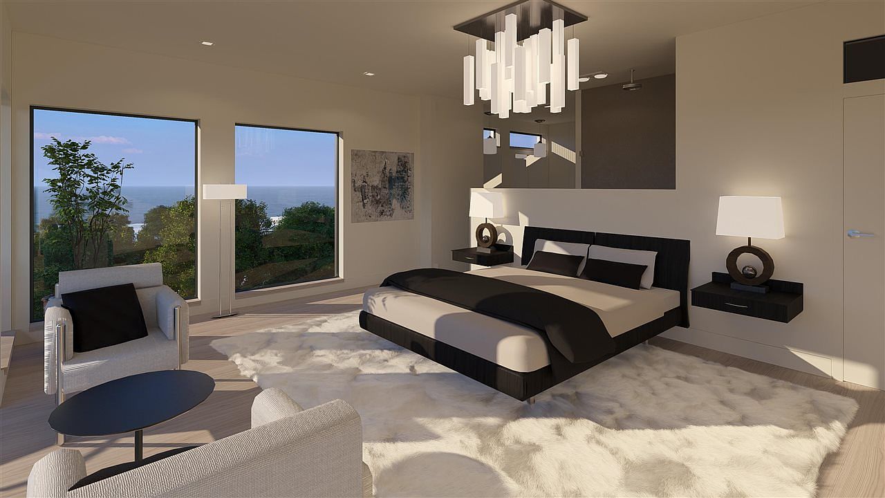 This is a modern primary bedroom featuring a large bed with black and white bedding, floating nightstands with lamps, and a unique chandelier. Large windows offer a view of the ocean and greenery, while a plush white rug adds texture to the space. The room has a minimalist and luxurious feel.