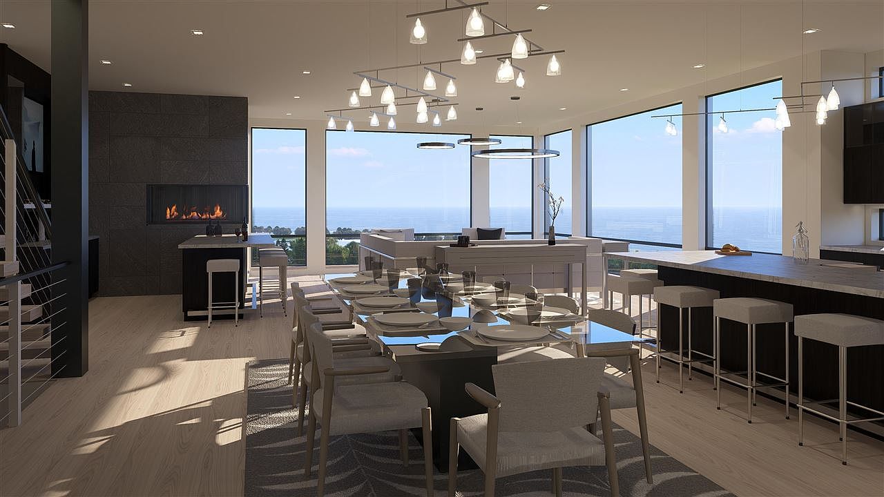 This is a spacious and modern dining room with a large dining table set for a meal. The room features floor-to-ceiling windows offering stunning ocean views, and contemporary lighting fixtures hang above the table. The open floor plan seamlessly connects the dining area to the living space, creating an inviting and luxurious atmosphere.