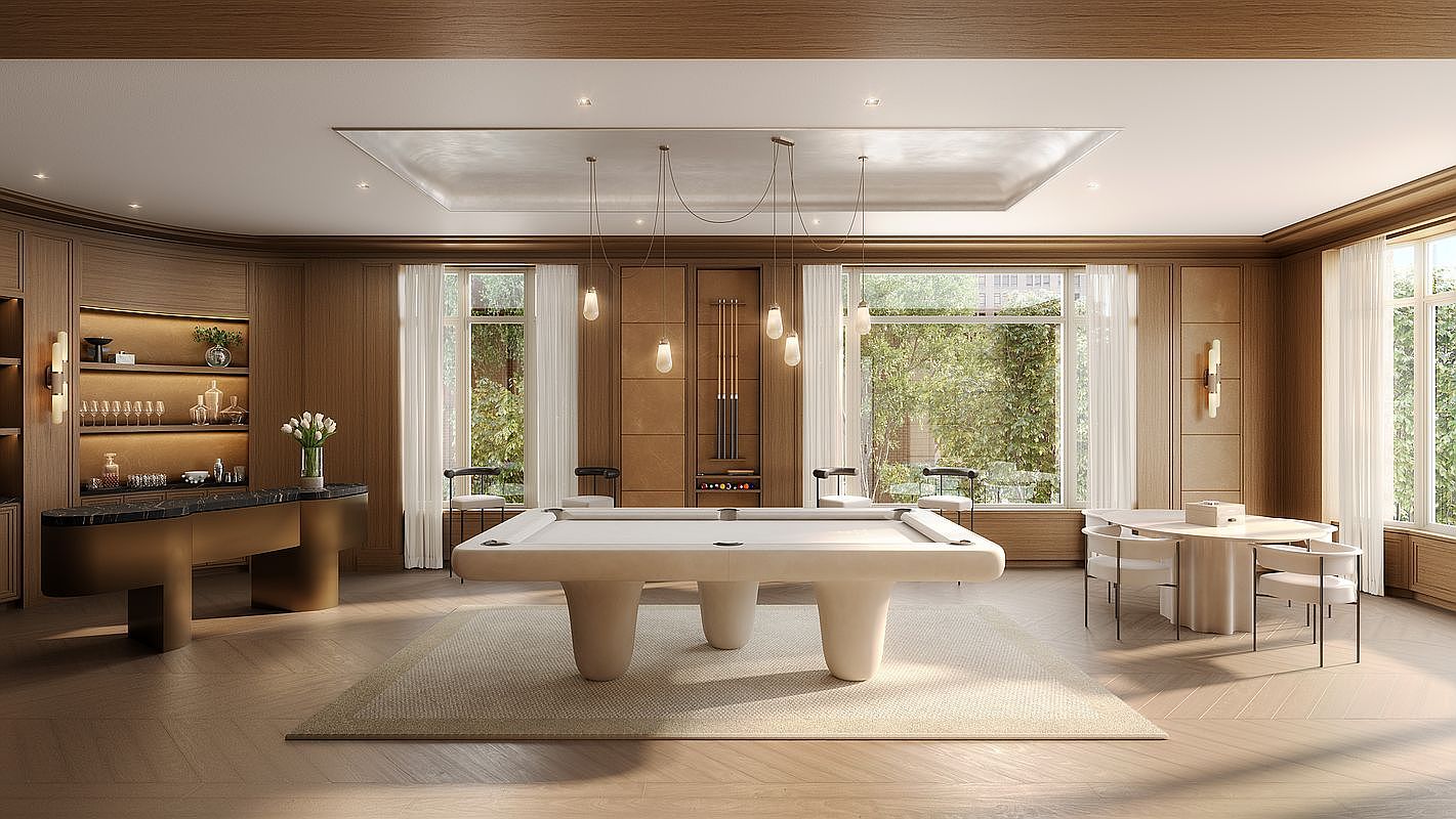 This sophisticated game room features a central billiards table with a minimalist design, set upon a large area rug over light-toned herringbone wood flooring. The space is anchored by a custom bar area with illuminated shelving on the left and a circular dining table with modern seating on the right. Large windows with sheer curtains allow natural light to fill the room, which is finished with warm wood-paneled walls and a recessed ceiling detail.