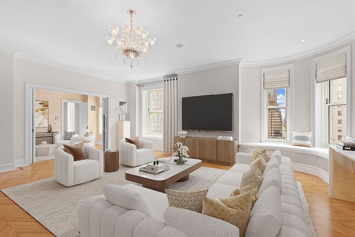 This elegant living room features a sophisticated neutral color palette, highlighted by a large, plush sectional sofa and two matching armchairs arranged around a low-profile coffee table. The space is anchored by a crystal chandelier and a large television mounted above a light wood media console, while a curved window seat offers a view of the city skyline. The room is finished with herringbone-patterned wood flooring and a large area rug, creating a bright and airy atmosphere.