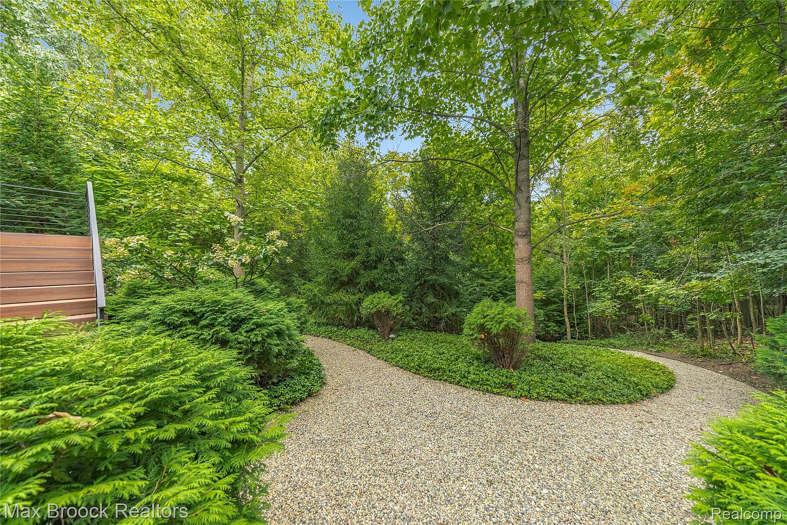This image showcases a beautifully landscaped yard or garden area. A winding gravel path meanders through lush greenery, including mature trees, shrubs, and ground cover. The scene evokes a sense of tranquility and natural beauty, highlighting the property's outdoor appeal.