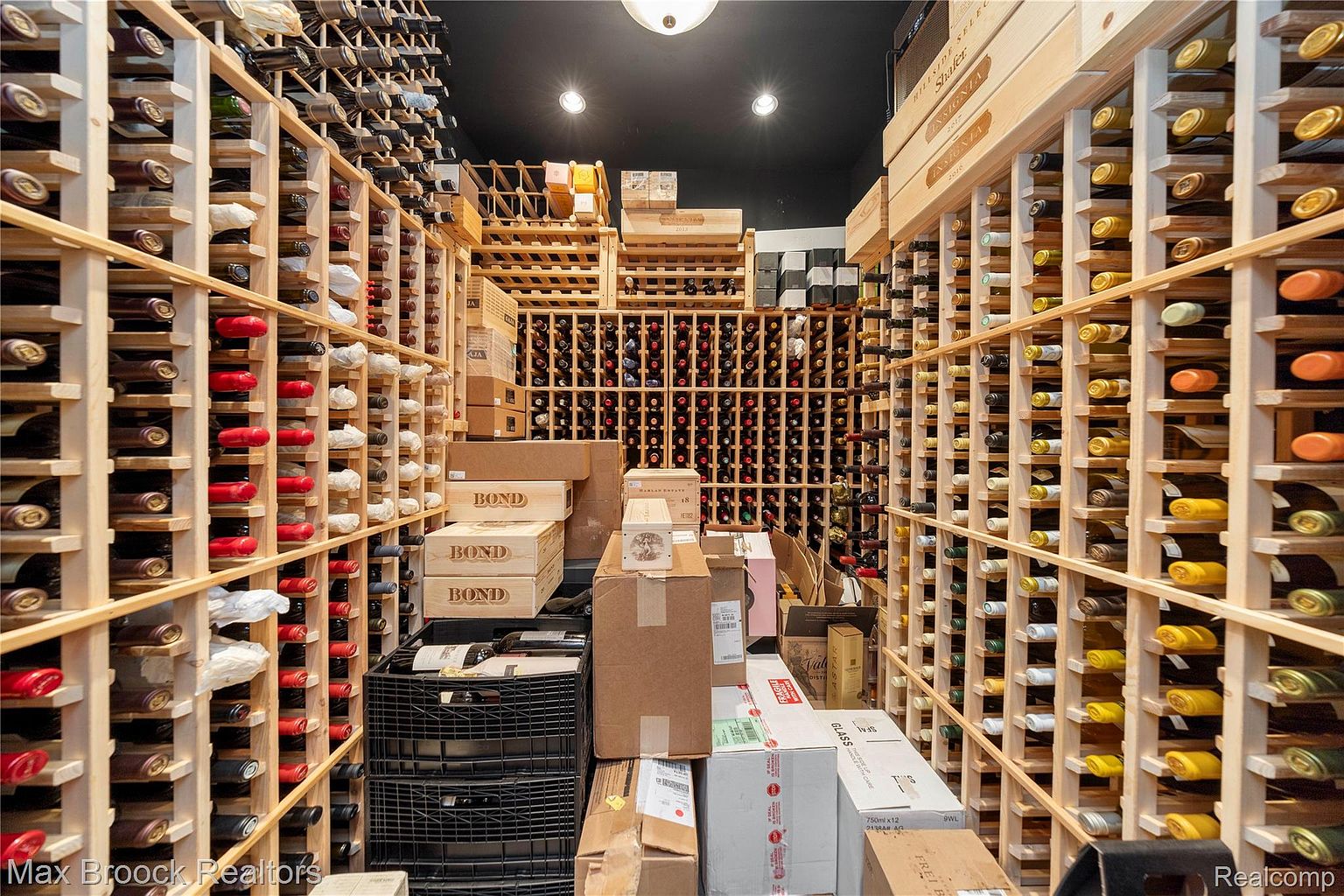 This image showcases a well-stocked wine cellar, featuring wooden racks filled with numerous bottles of wine. Boxes and crates are stacked throughout the space, suggesting a substantial collection. The lighting is dim, creating a classic and sophisticated ambiance, perfect for wine enthusiasts.