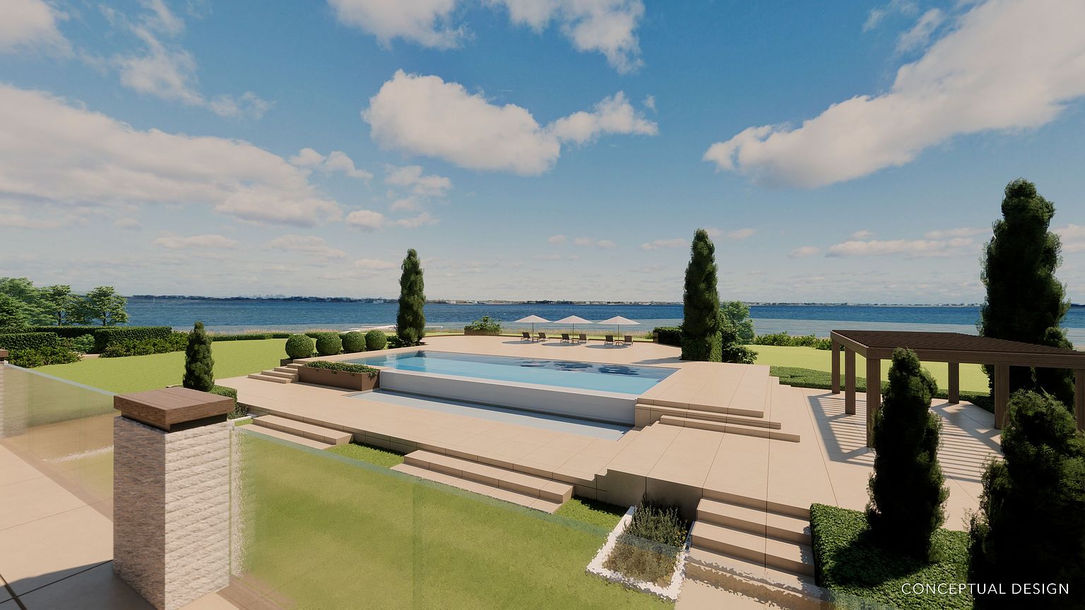 This image showcases a luxurious outdoor pool area with a modern design. The rectangular pool is surrounded by a light-colored tiled deck, manicured lawns, and neatly trimmed trees. In the background, the ocean and sky create a serene backdrop, enhancing the property's appeal as a high-end retreat.