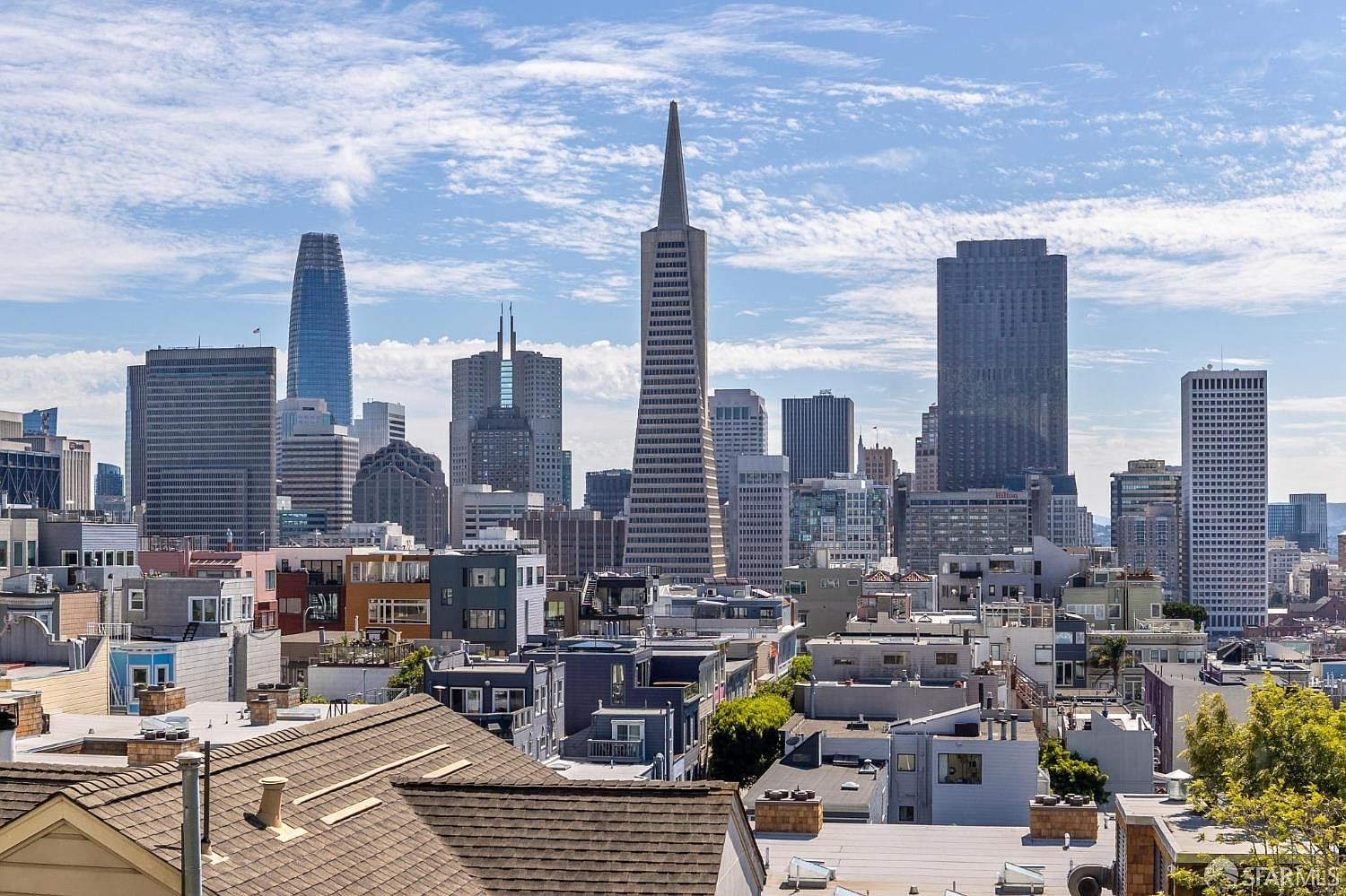 This aerial view showcases a dense urban landscape with a mix of residential buildings and towering skyscrapers. The architectural styles vary, creating a dynamic skyline against a partly cloudy sky. The image provides a sense of the city's scale and the proximity of residential areas to the central business district.