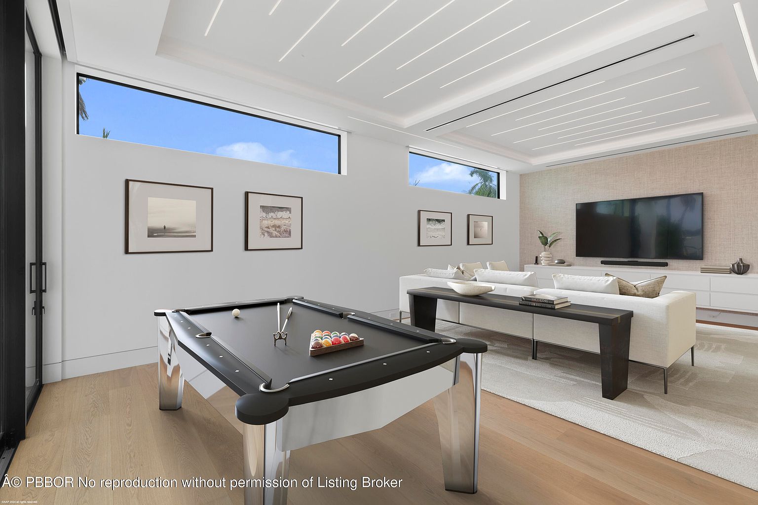 This interior shot showcases a modern living room featuring a pool table as a central element. The room is well-lit with natural light streaming through high windows, complemented by contemporary ceiling lighting. A sleek sofa and entertainment unit with a large television create a comfortable and stylish living space, enhanced by neutral tones and minimalist decor.
