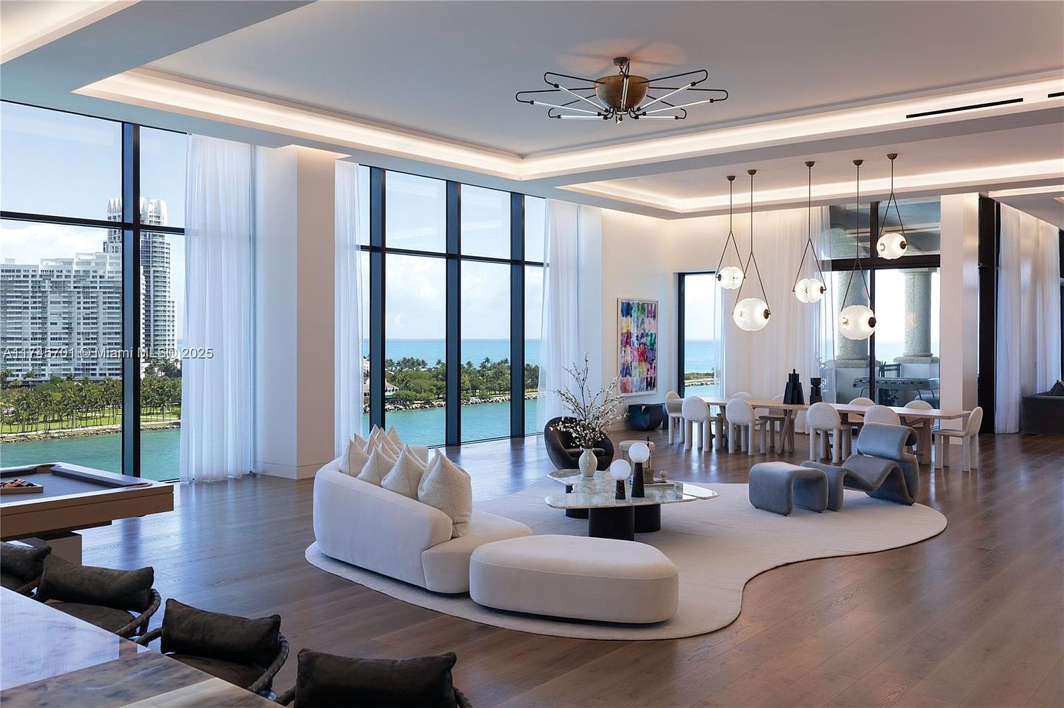 This is a spacious and luxurious living room with floor-to-ceiling windows offering stunning ocean views. The room features a modern white sofa, a unique coffee table, and stylish lighting fixtures. The open floor plan seamlessly connects the living area to the dining space, creating an inviting and elegant atmosphere.
