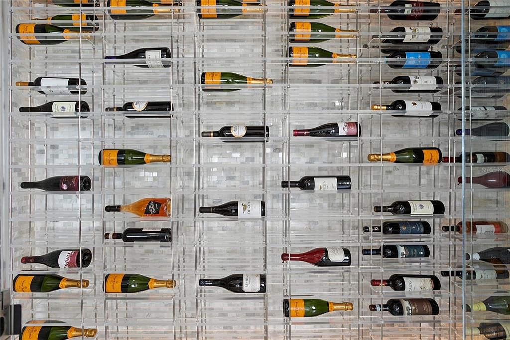 The image showcases a modern wine cellar featuring a grid-like display system holding numerous wine bottles. The bottles are arranged horizontally, showcasing a variety of labels and colors. The overall impression is one of organized elegance and sophistication, ideal for a wine enthusiast's home.