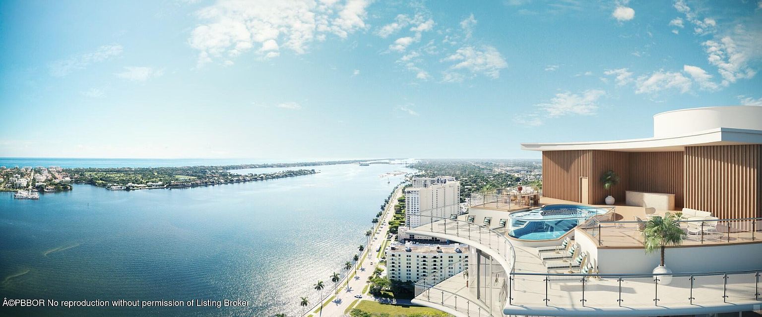 This aerial view showcases a luxurious penthouse with a private pool and deck overlooking a stunning coastal landscape. The building's modern architecture is complemented by the serene blue waters and lush greenery, creating an impression of upscale living and breathtaking views. The image highlights the property's prime location and exclusive amenities.