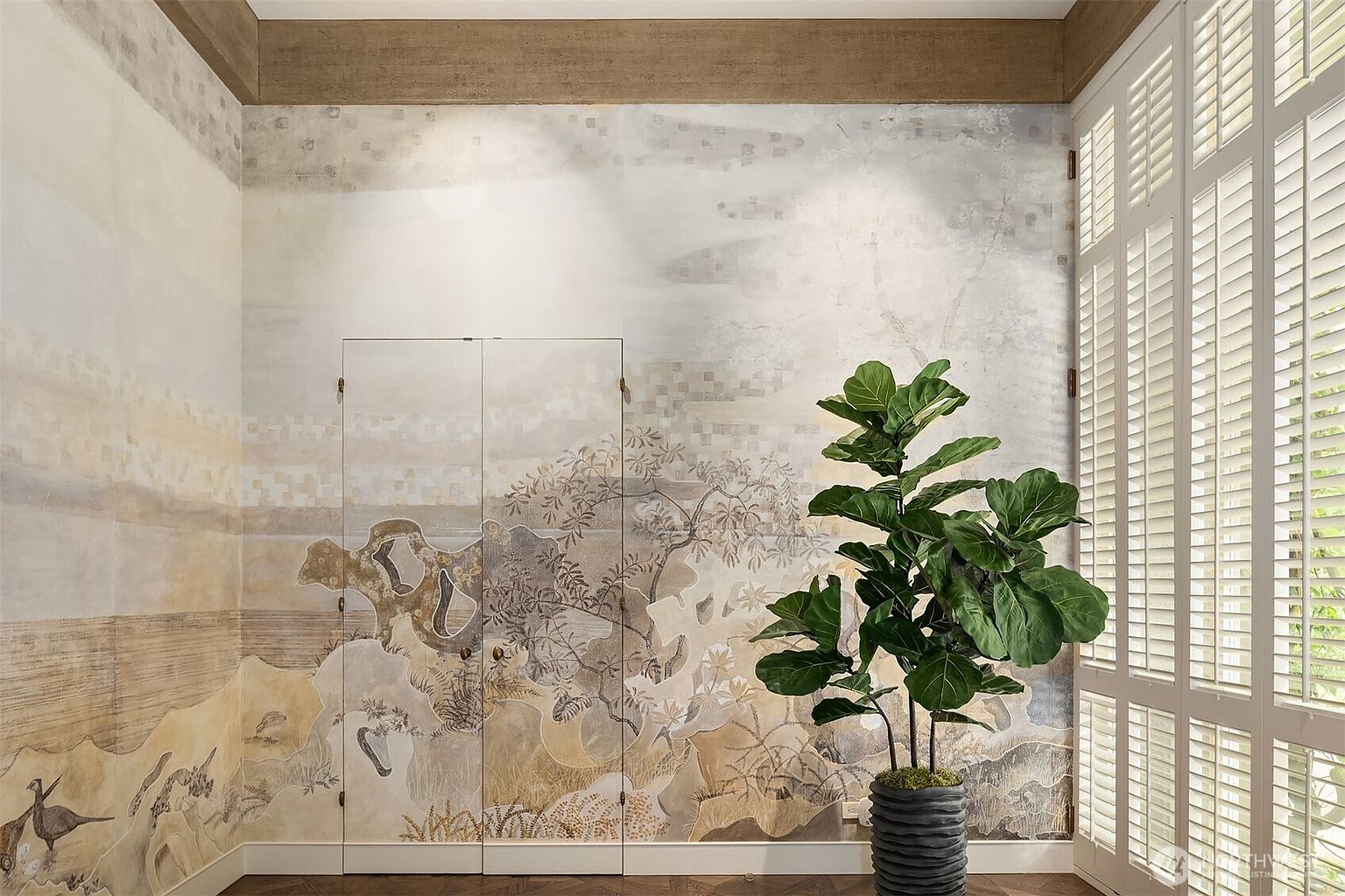 This interior shot showcases a unique bedroom with custom wall art depicting a landscape scene, complemented by a large potted fiddle-leaf fig tree. Natural light streams in through shuttered windows, highlighting the hardwood flooring and creating a serene atmosphere. The room's design blends artistic elements with natural textures, offering a tranquil and sophisticated space.