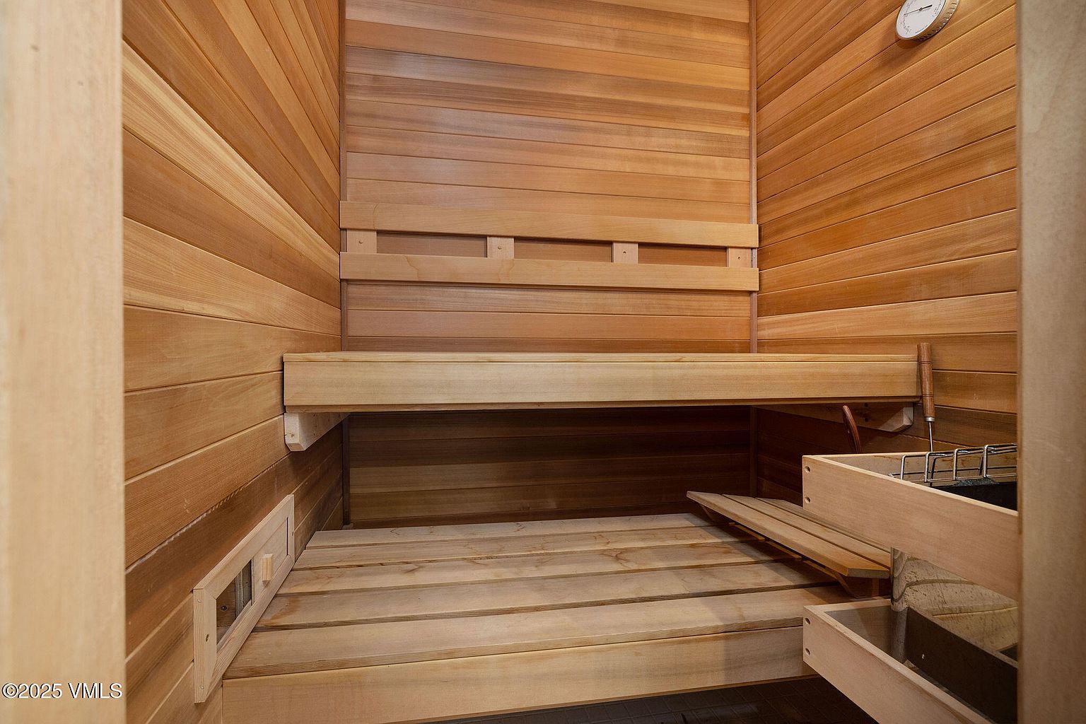 This image showcases the interior of a sauna, featuring wooden walls, benches, and flooring. The warm tones of the wood create a relaxing and inviting atmosphere, perfect for a home gym or wellness space. The sauna is well-lit and appears to be in excellent condition, highlighting its potential as a desirable amenity.